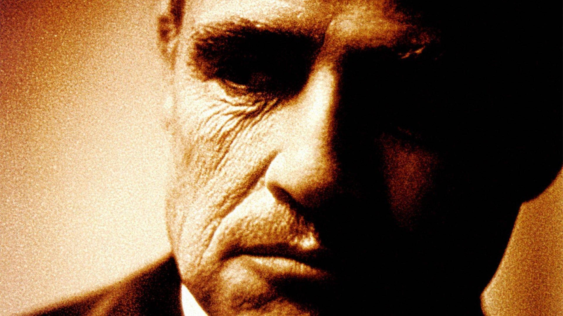 The Godfather 桌布 壁紙 — 飽經風霜的男人臉部特寫，戲劇性的棕褐色燈光，深邃陰影和強烈眼神。