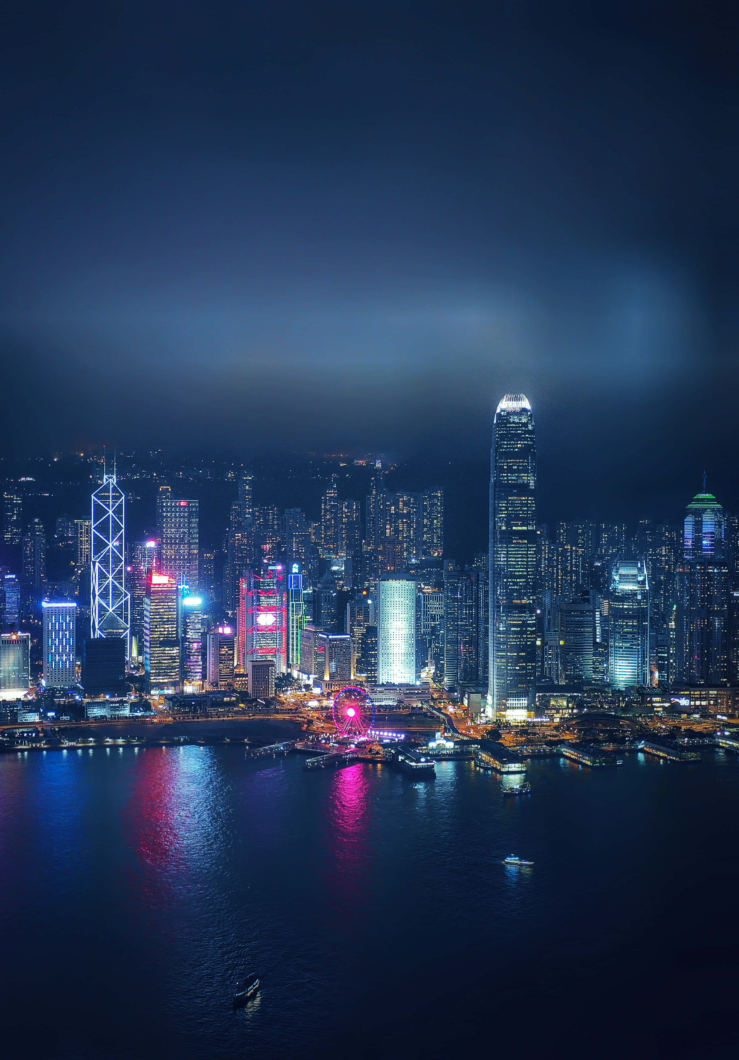 Night Time 桌布 壁紙 — 香港令人目眩的夜景，摩天大樓在漆黑的天空下閃耀，燈光倒映在下方水面。