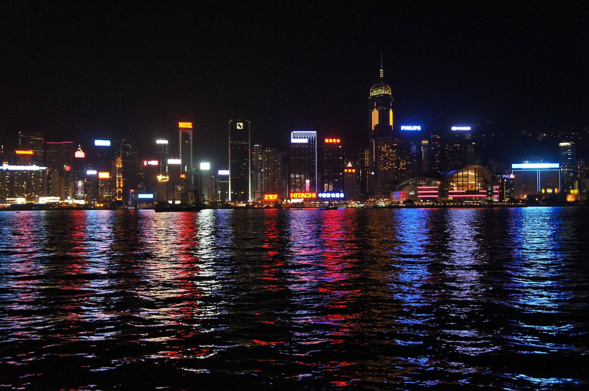 城市 桌布 壁紙 — 香港令人目眩的夜景，霓虹燈照亮的高樓大廈倒映在漆黑的水面上。