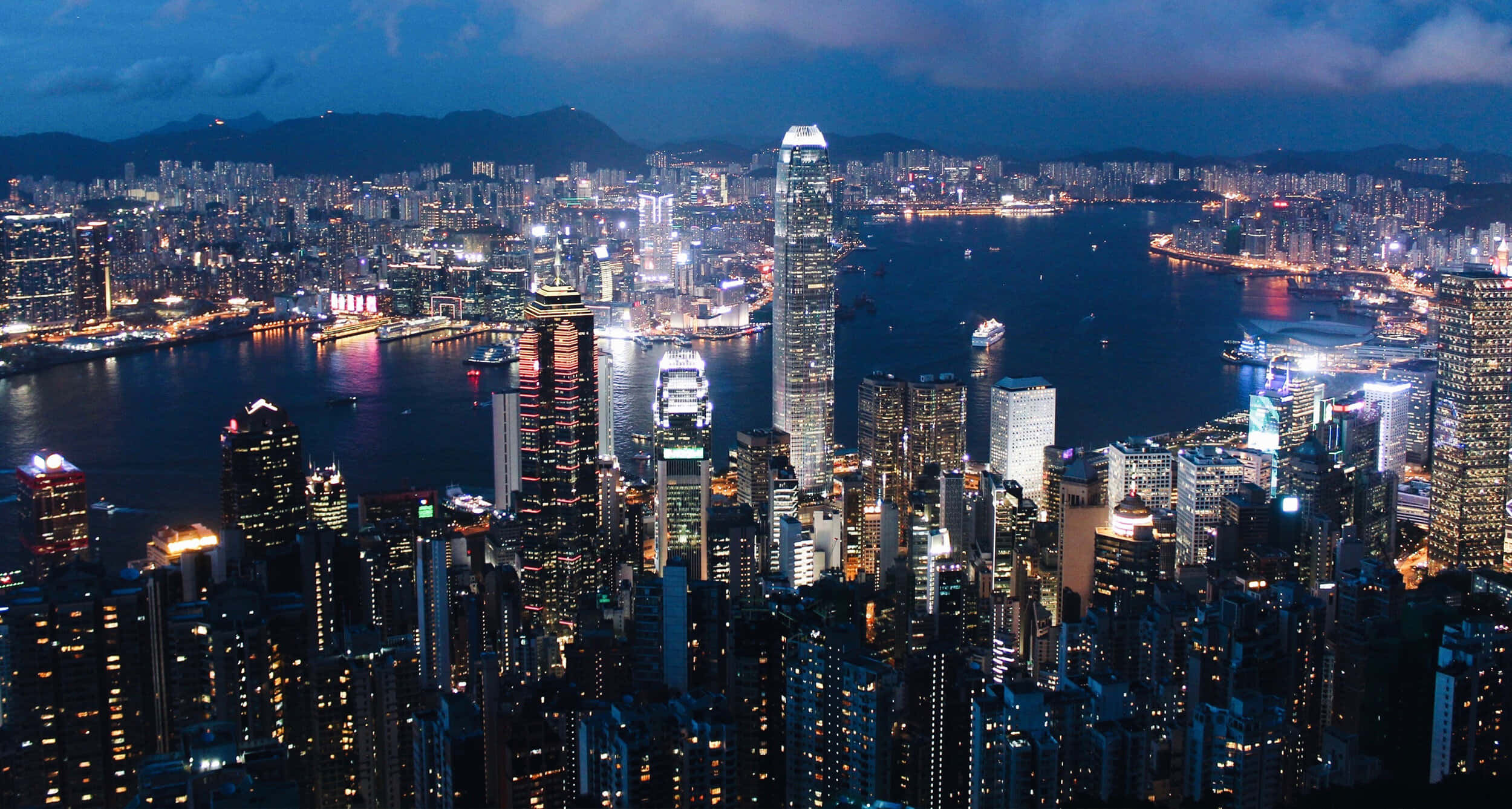 香港 桌布 壁紙 — 香港令人目眩的夜景，高聳的摩天大樓在黑暗的天空中閃耀，港口點綴著燈光。