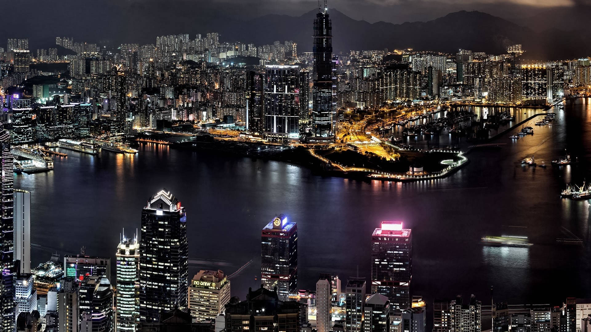 德黑蘭 桌布 壁紙 — 香港令人目眩神迷的夜景，閃爍的摩天大樓倒映在港口水面上。