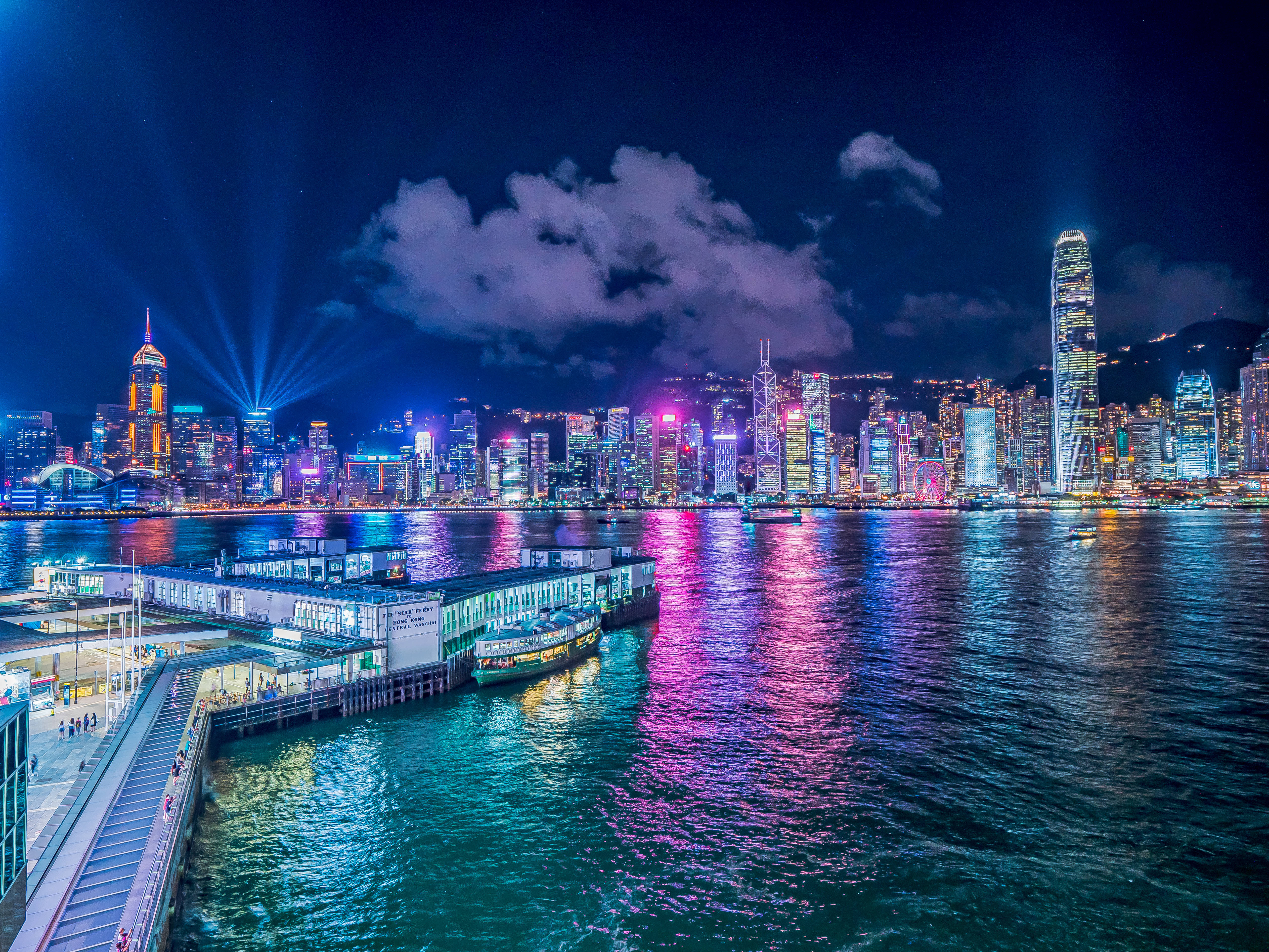 香港 桌布 壁紙 — 香港令人驚嘆的夜景，霓虹燈光倒映在水面上，摩天大樓射出雷射光束。