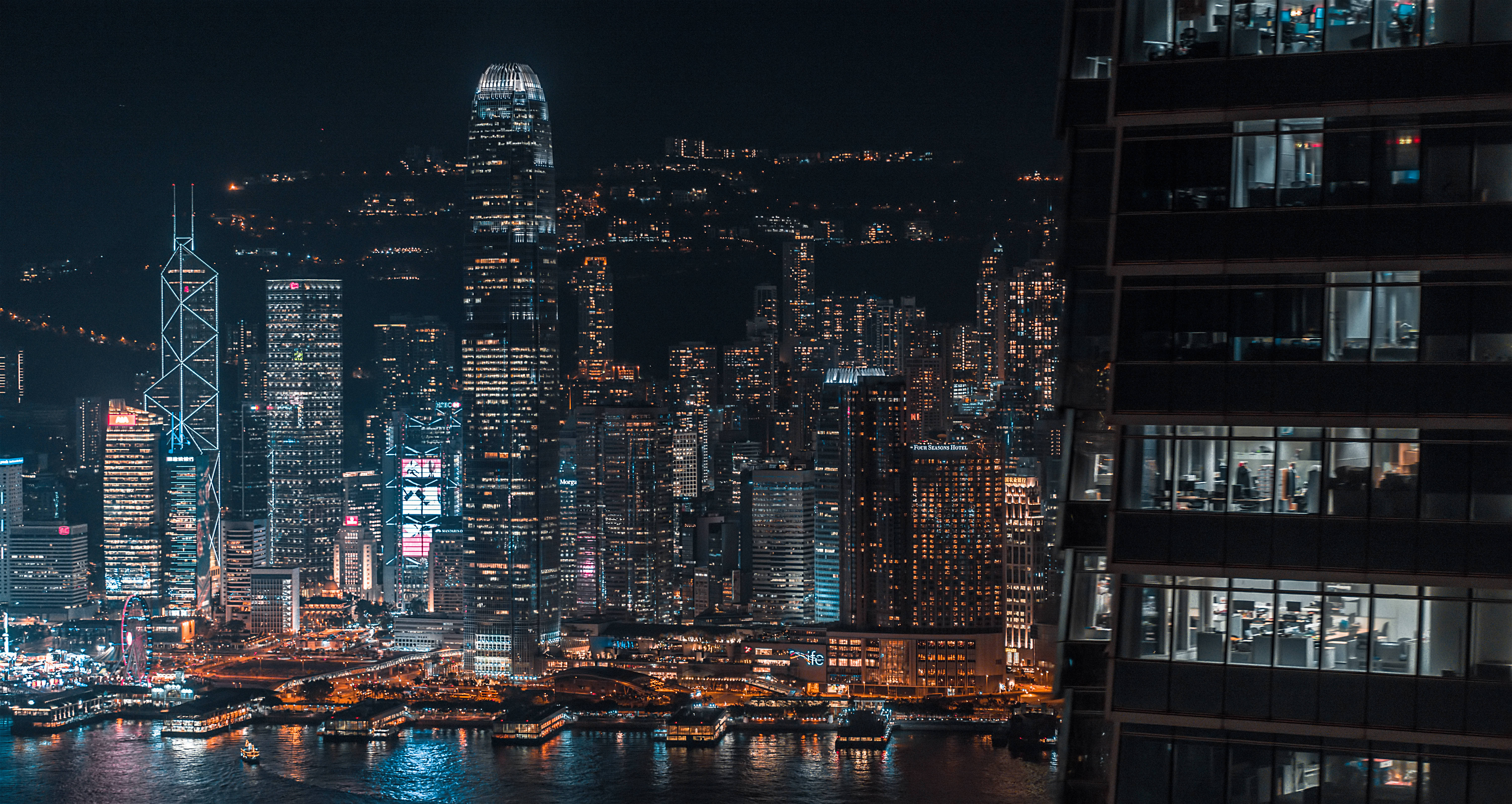 香港 桌布 壁紙 — 香港令人驚嘆的夜景，高聳的摩天大樓將霓虹燈反射在港口水面上。