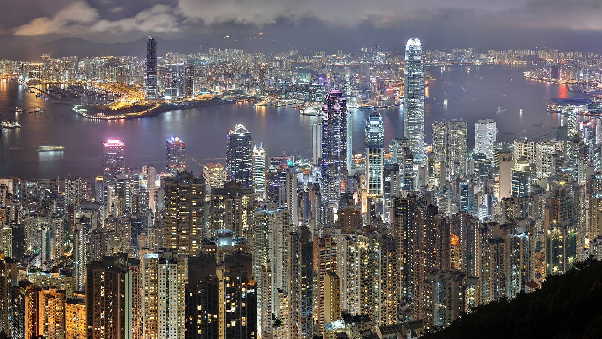 城市風景 桌布 壁紙 — 香港令人驚嘆的夜景，高聳的摩天大樓在黑暗的天空中閃耀，港口反射著燈光。