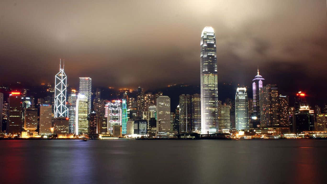 1366x768 桌布 壁紙 — 香港夜景，摩天大樓在陰天下的平靜水面上倒映著燈光。