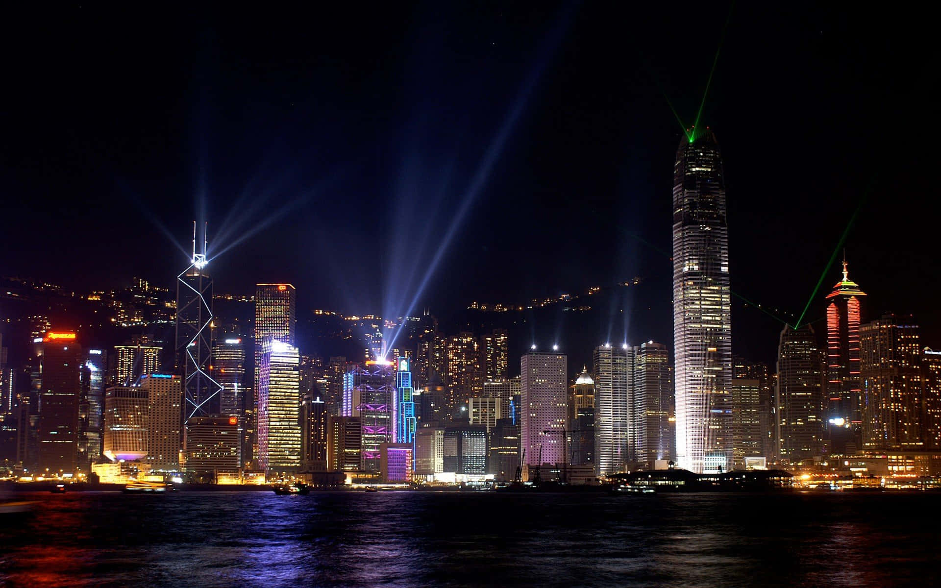 City Night 桌布 壁紙 — 香港夜景，璀璨的雷射光束和色彩繽紛的摩天大樓燈光倒映在水面上。