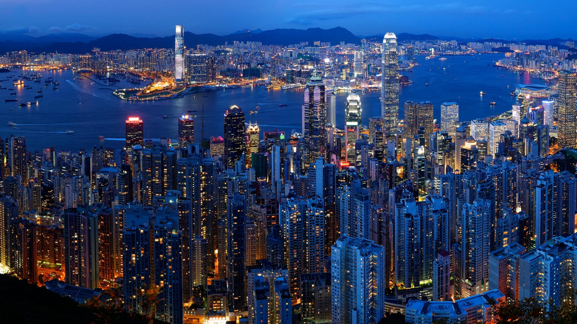 Mojave 桌布 壁紙 — 香港天際線在黃昏時的壯麗航拍圖，閃爍的摩天大樓倒映在港灣水面上。