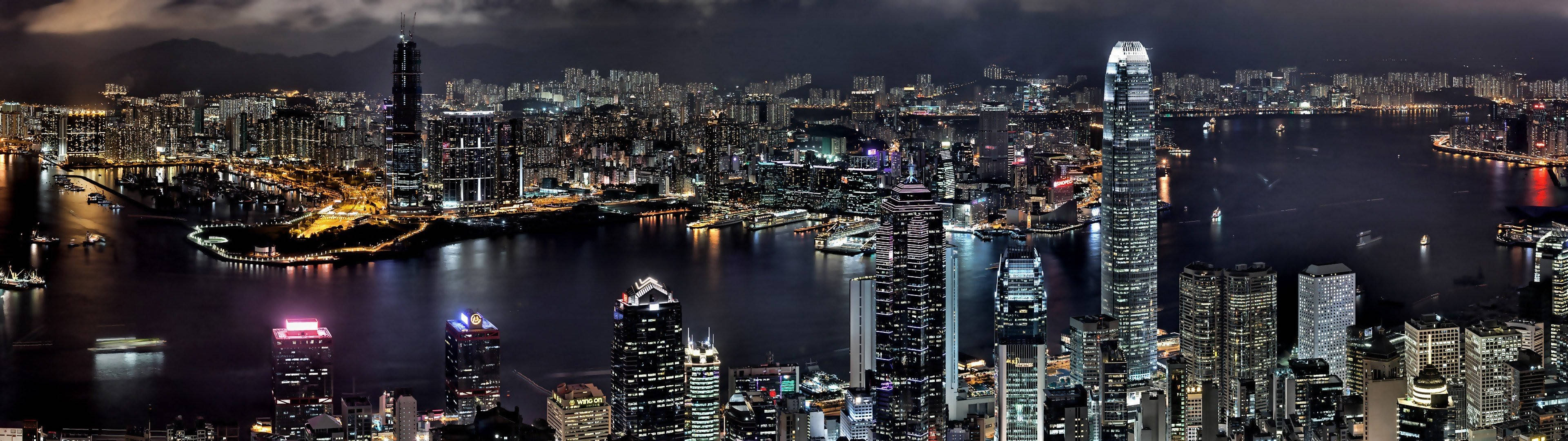3840x1080 HD dual monitor 桌布 壁紙 — 香港天際線的 panoramatic 夜景，閃爍的摩天大樓和充滿船隻的活力港口。