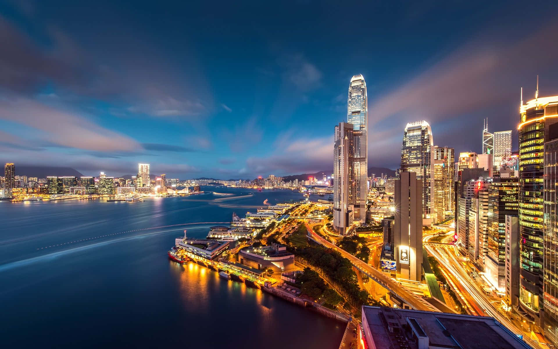 桌布 壁紙 — 香港天際線的壯麗夜景，閃爍的摩天大樓和充滿活力的海港倒映著城市燈光。