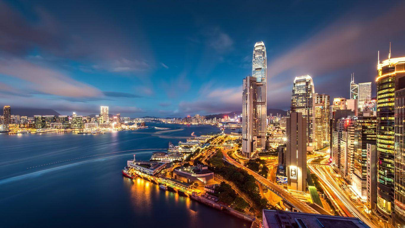 夜空 桌布 壁紙 — 香港天際線的壯麗黃昏景色，閃爍的摩天大樓倒映在港口水面上。