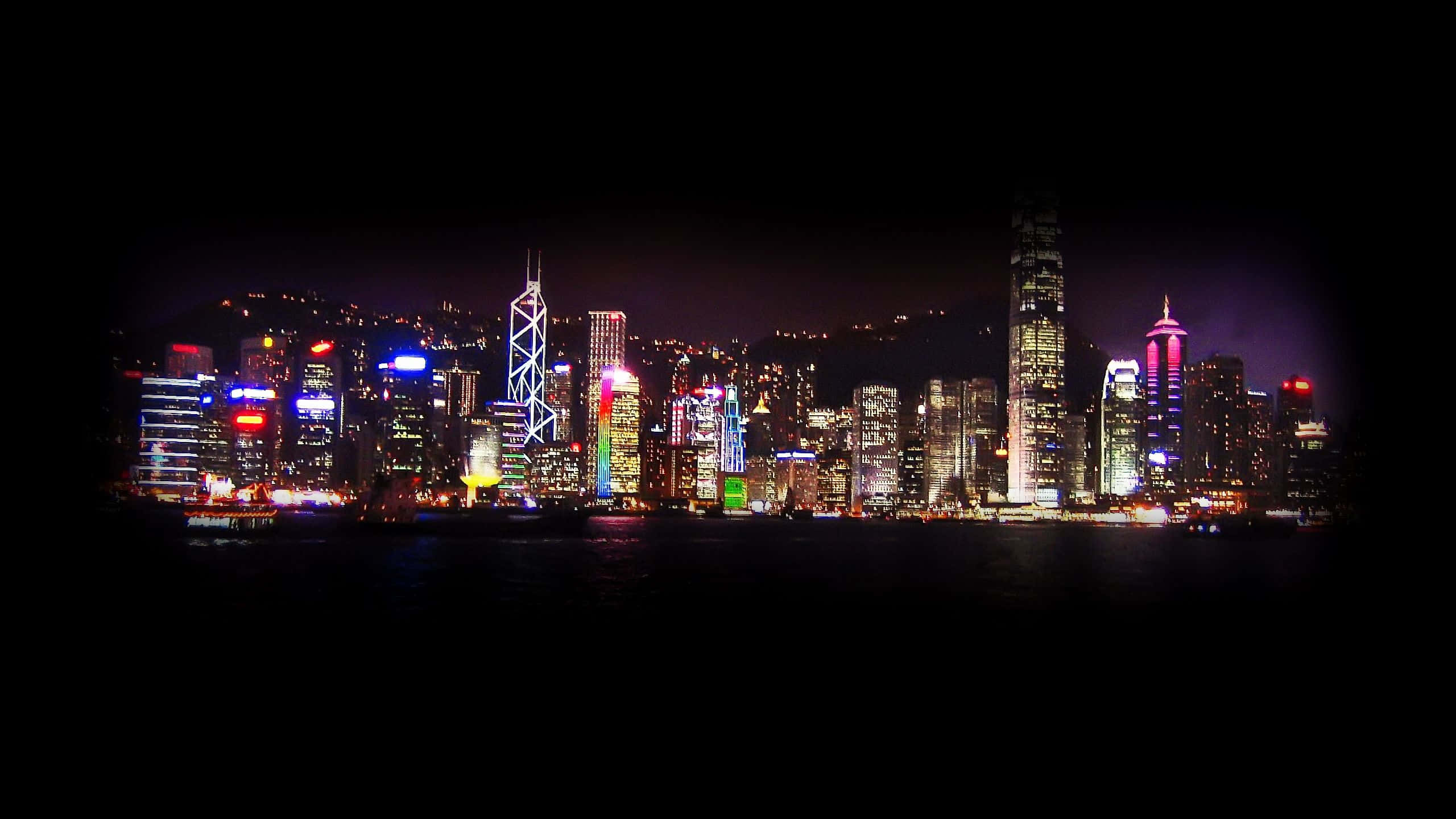 Aesthetic YouTube Banner 桌布 壁紙 — 香港天際線的迷人夜景，霓虹燈閃爍的摩天大樓倒映在黑暗的水面上。