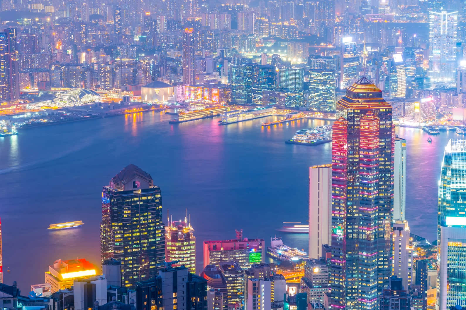 香港 桌布 壁紙 — 香港天際線的迷人夜景鳥瞰圖，閃爍的摩天大樓倒映在港灣水面上。