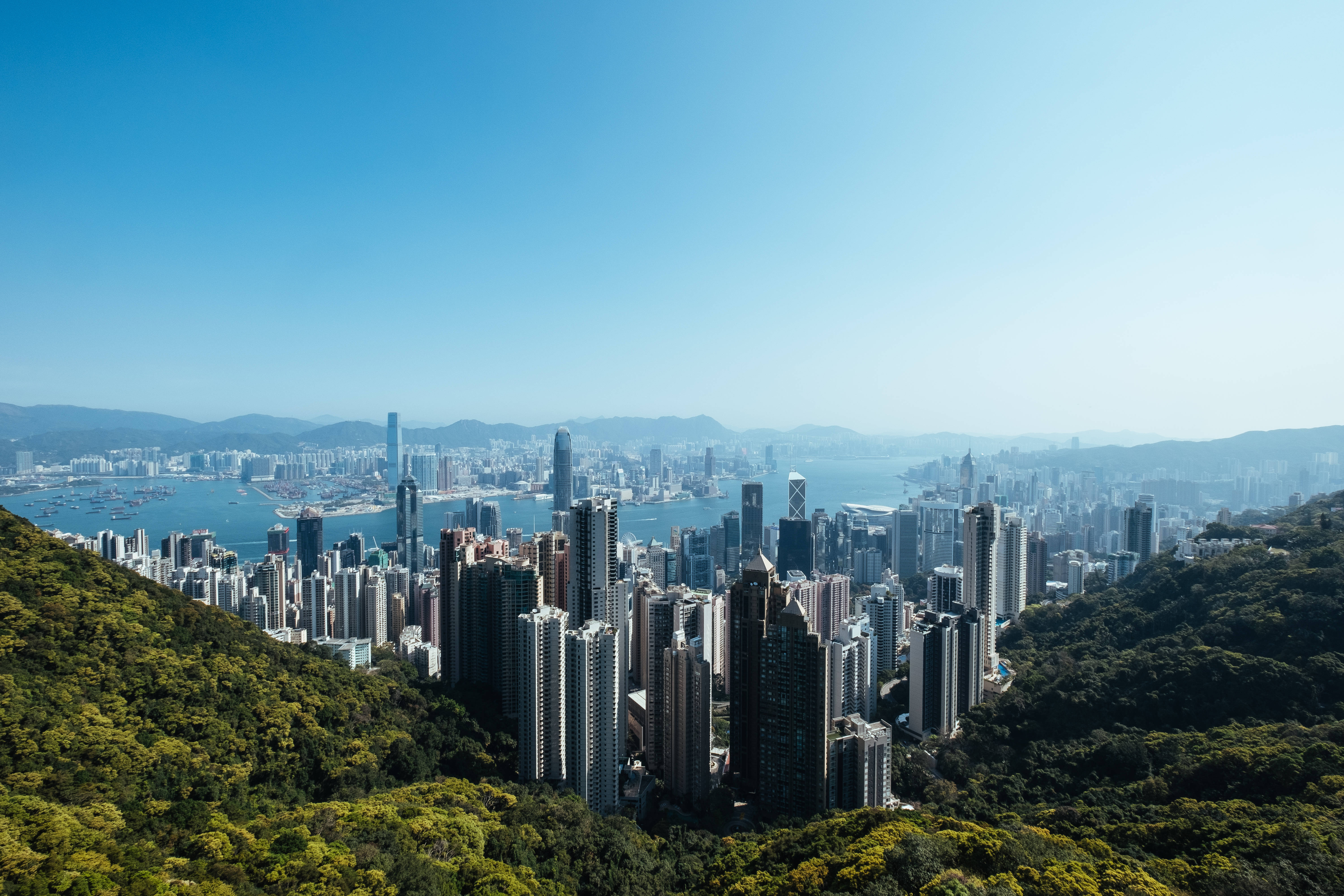 香港 桌布 壁紙 — 香港密集的天際線全景，坐落於翠綠山丘之間，藍天白雲。