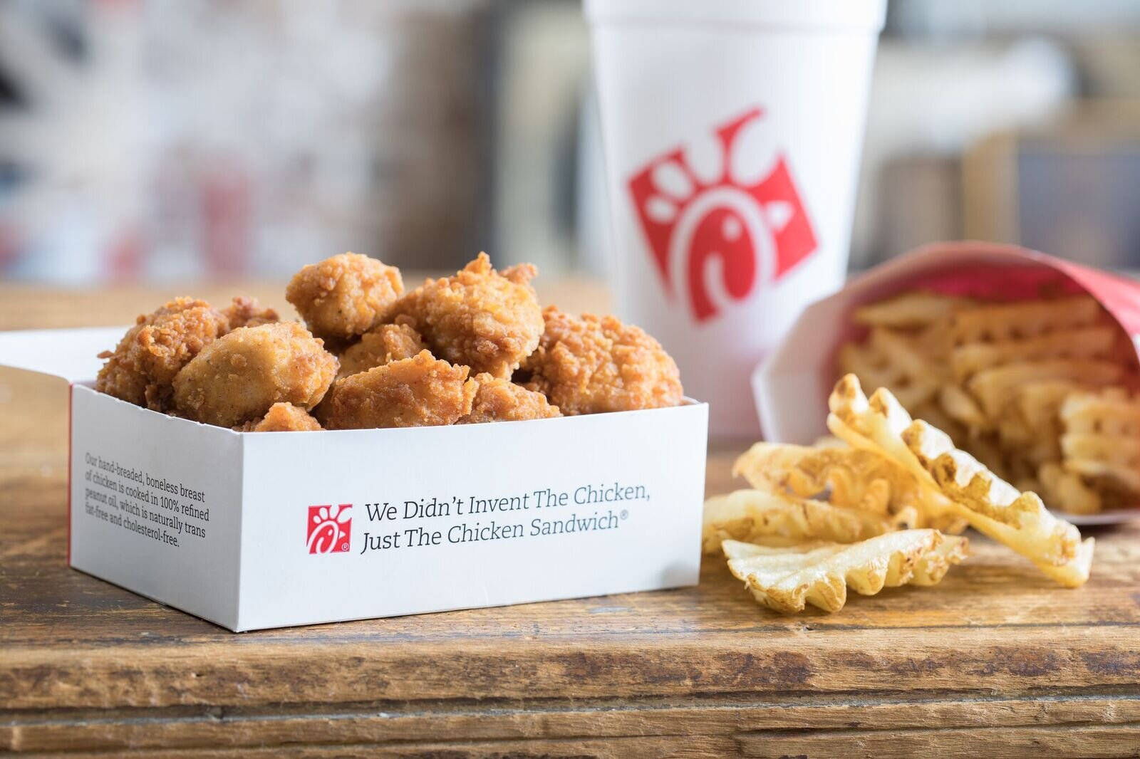chick 桌布 壁紙 — 香脆炸雞塊和格子薯餅放在一個質樸的木桌上，旁邊有一個Chick-fil-A飲料杯。