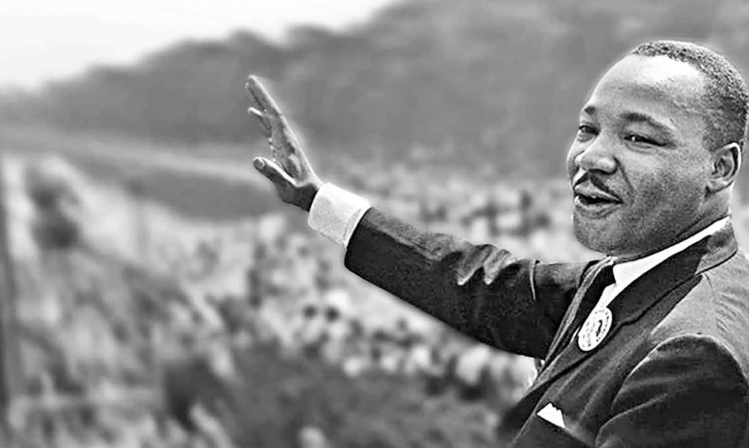 Mlk 桌布 壁紙 — 馬丁·路德·金在歷史性演講中向人群揮手，黑白照片，背景柔和模糊。