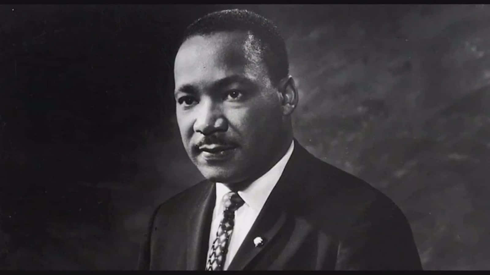 Mlk 桌布 壁紙 — 馬丁·路德·金的莊嚴黑白肖像，身穿西裝打領帶，背景是深色有紋理的。