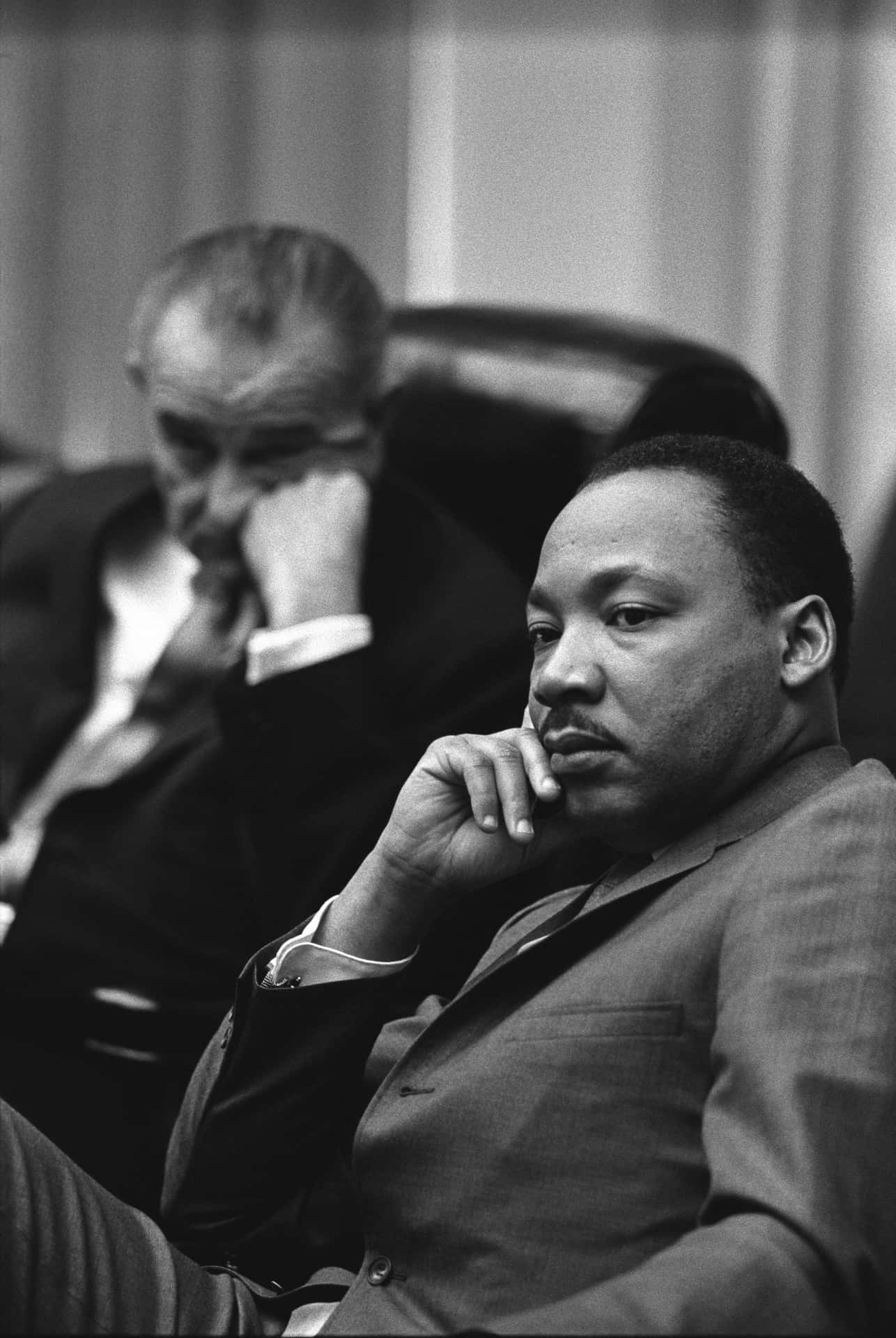 Martin Luther King Jr 桌布 壁紙 — 馬丁·路德·金身穿西裝的黑白肖像，手托下巴若有所思地坐著。