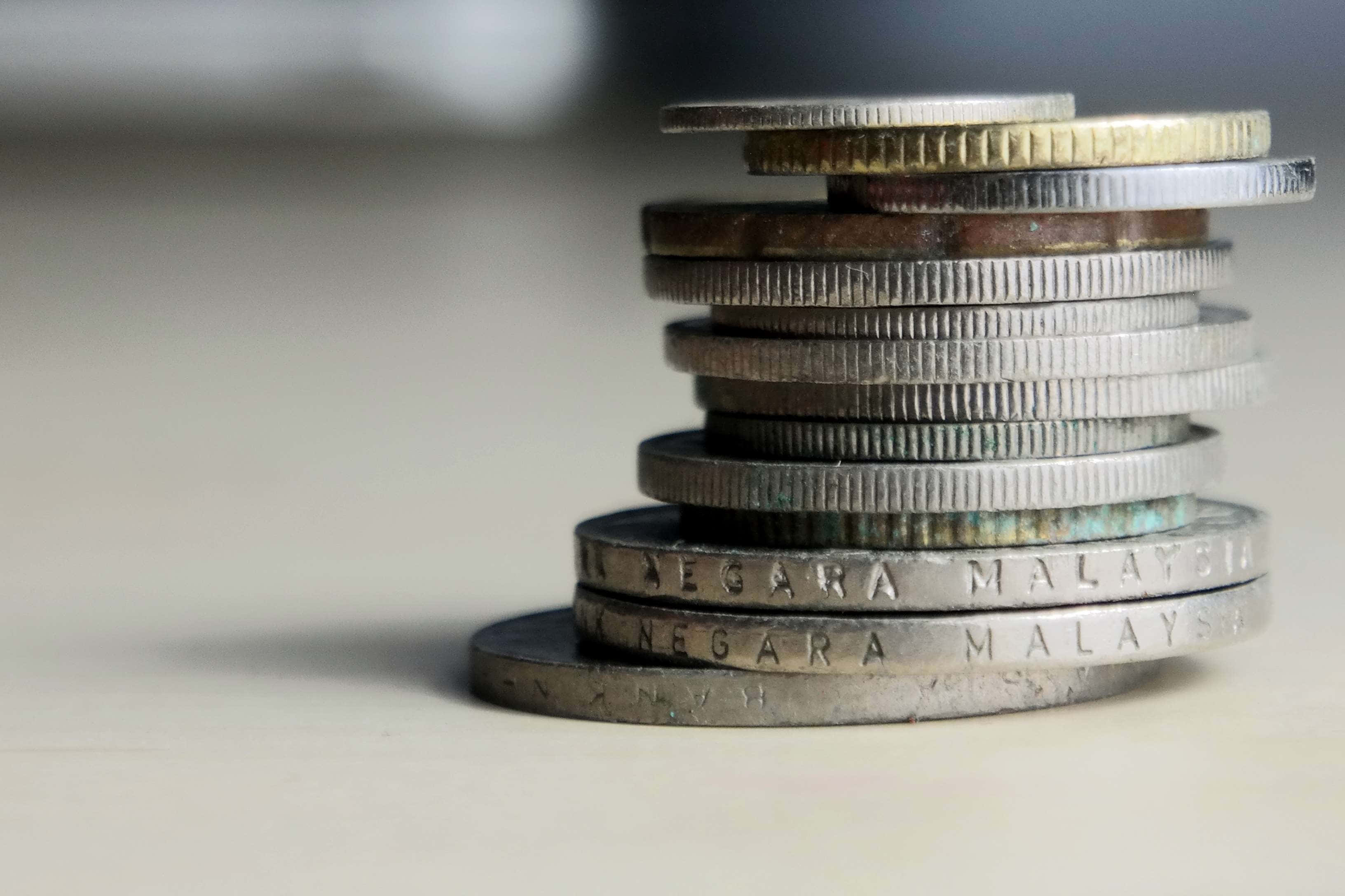 Coins 桌布 壁紙 — 馬來西亞硬幣的特寫堆疊，顯示磨損和雕刻文字，背景柔和模糊。