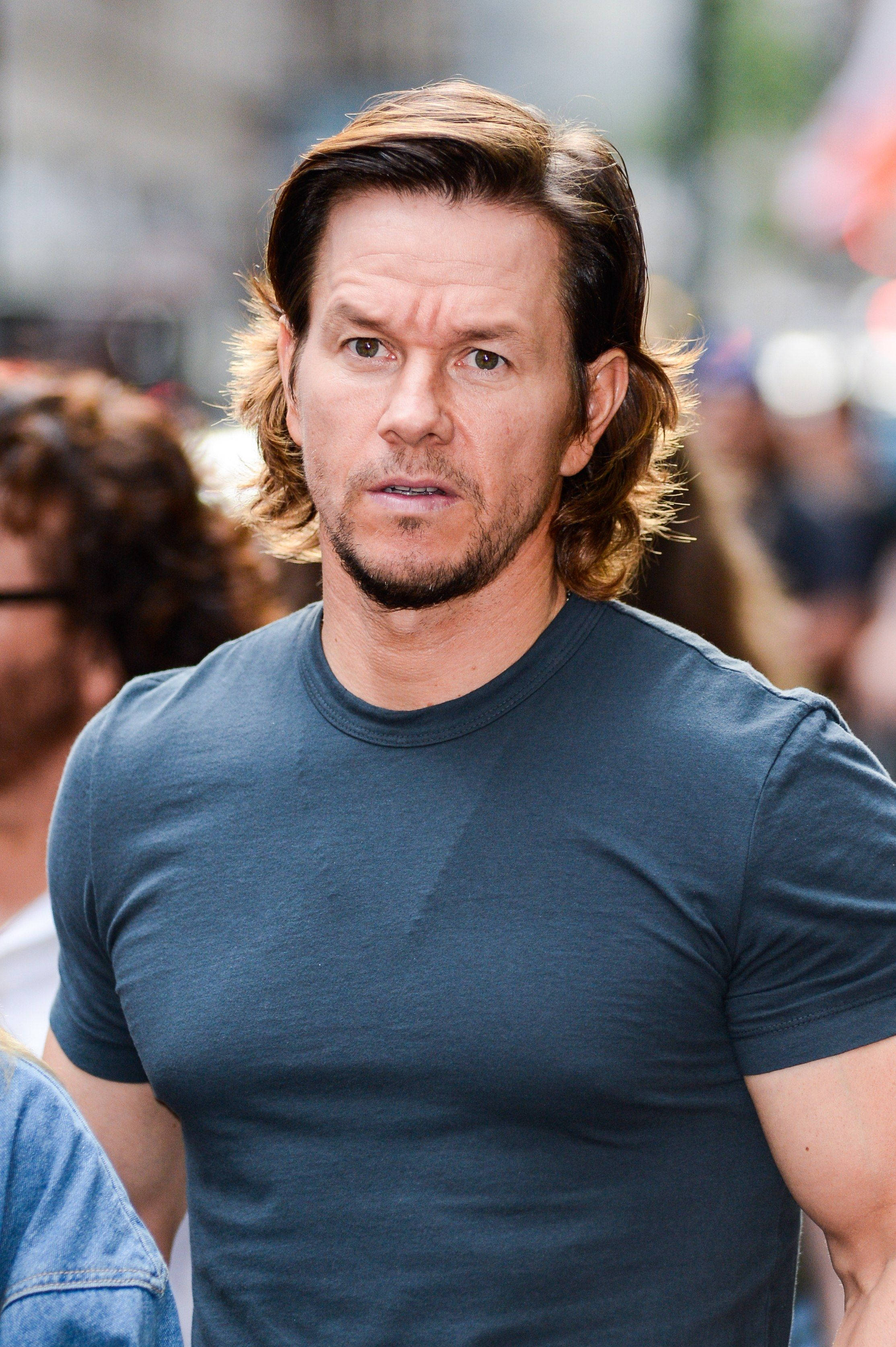 Mark Wahlberg 桌布 壁紙 — 馬克·華伯格在擁擠的城市街道上穿著深藍色T恤，專注地凝視。