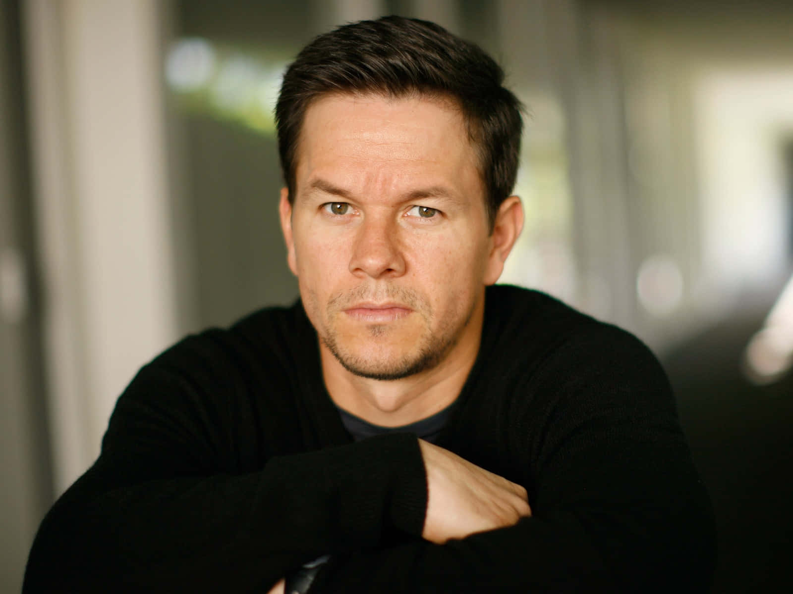 Mark Wahlberg 桌布 壁紙 — 馬克·華伯格雙臂交叉，在柔和光線的室內肖像中專注地凝視。