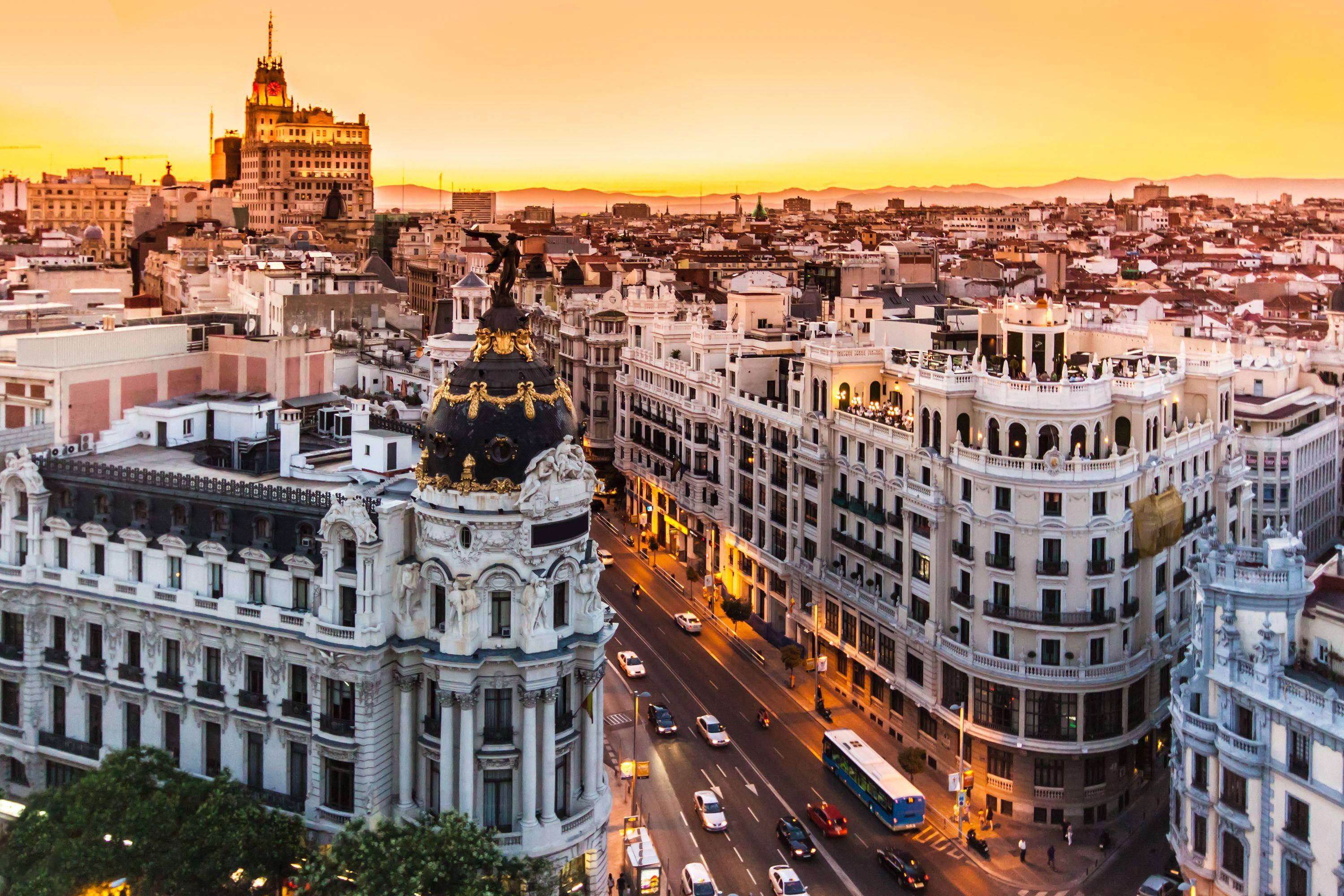 Madrid 桌布 壁紙 — 馬德里宏偉建築的鳥瞰圖，沐浴在金色日落光芒中，下方是繁華的街道。