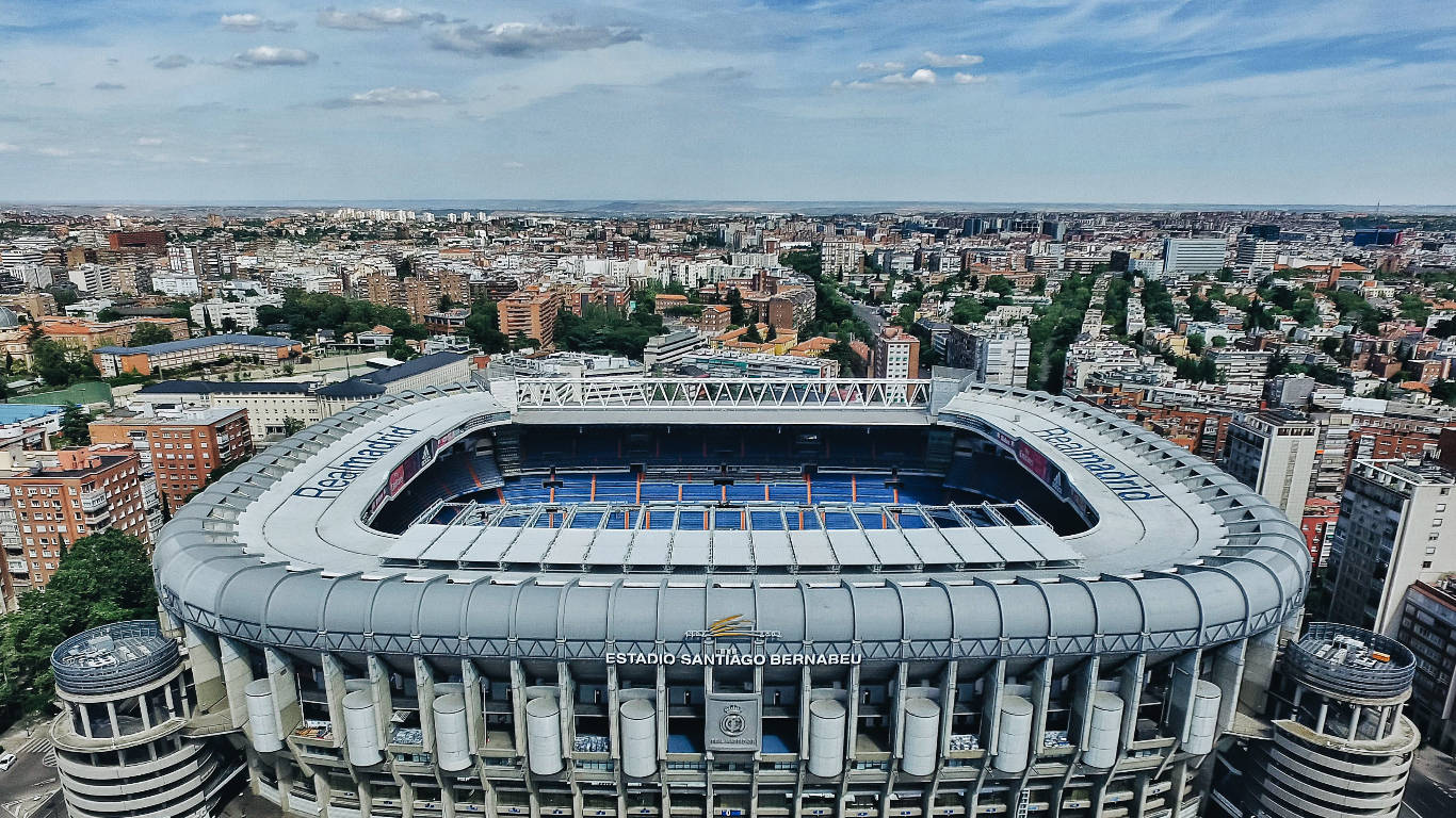 Madrid 桌布 壁紙 — 馬德里聖地亞哥·伯納烏球場的鳥瞰圖，周圍是密集的城市建築，天空部分多雲。