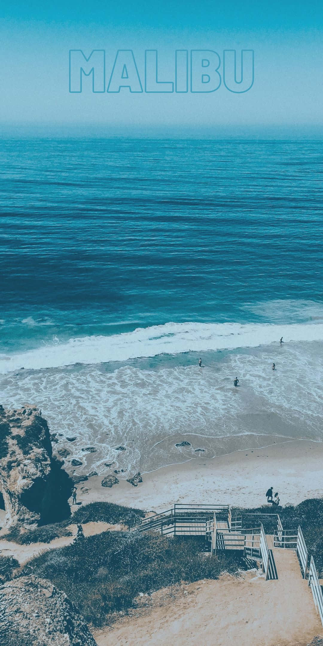 Beach Scene 桌布 壁紙 — 馬里布寧靜的海岸景觀，綠松石色的海浪拍打著岩石懸崖和木樓梯下的沙灘。
