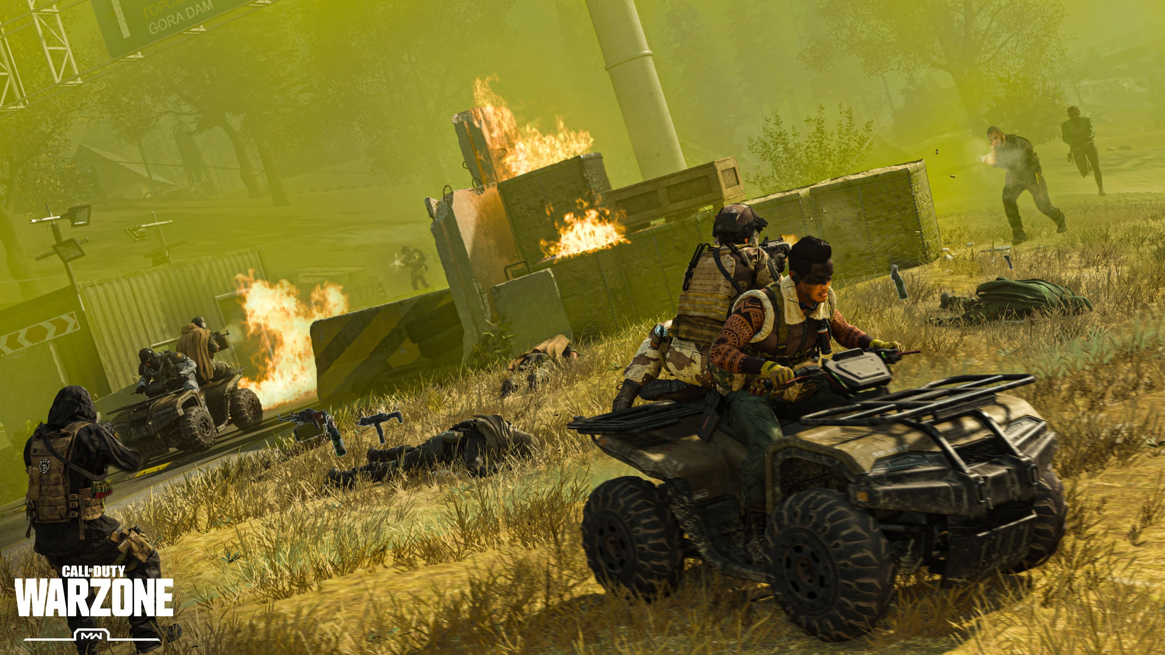 Warzone 桌布 壁紙 — 騎乘ATV的士兵在燃燒的戰場上穿梭，四周有燃燒的碎片和倒下的戰友，天空一片朦朧的黃色。