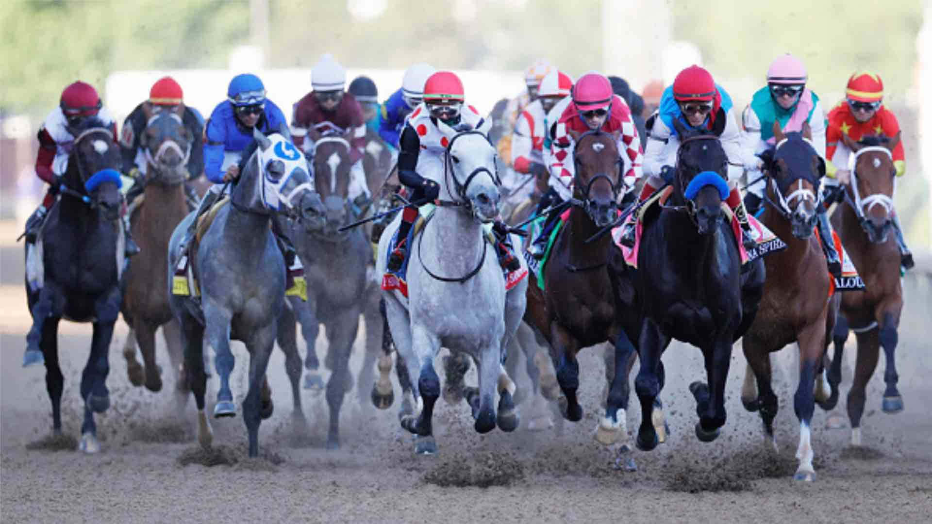 Kentucky Derby 桌布 壁紙 — 騎師戴著色彩繽紛的頭盔，騎著奔騰的馬匹在陽光普照的賽道上揚起塵土。