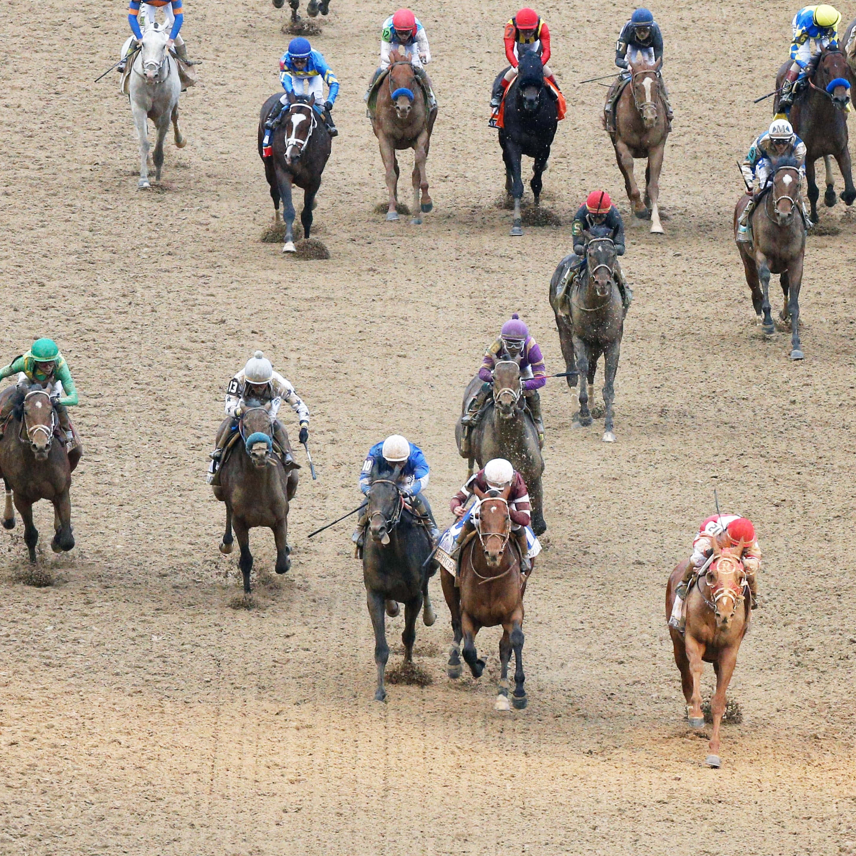 Kentucky Derby 桌布 壁紙 — 騎師身穿色彩繽紛的綵衣，在塵土飛揚的泥地賽道上高速策騎純種馬，濺起泥濘。