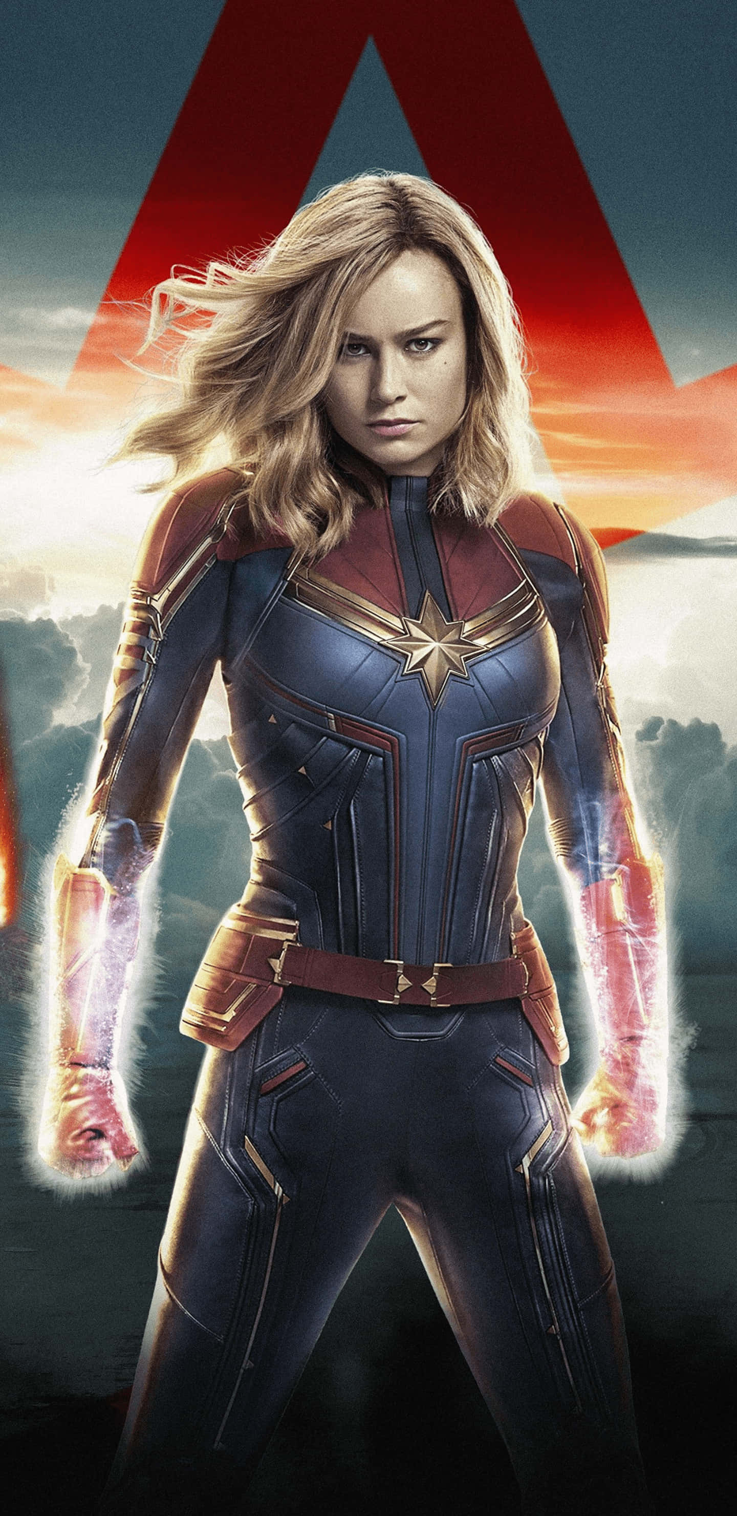 Pixel 3xl Captain Marvel 桌布 壁紙 — 驚奇隊長在夕陽天空下強勢站立，拳頭散發出發光的能量，身後有一個巨大的紅色A標誌。
