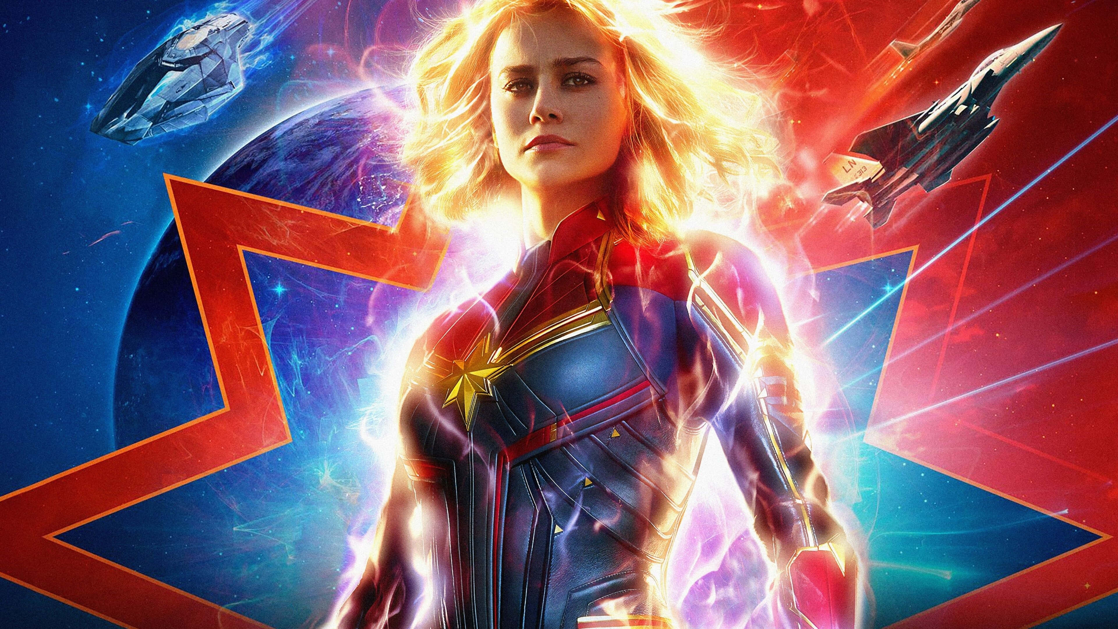 4K Marvel 壁紙 桌布 壁紙 — 驚奇隊長在太空中強勢站立，散發著發光的能量，身後有行星和戰鬥機，背景是宇宙的紅色和藍色。