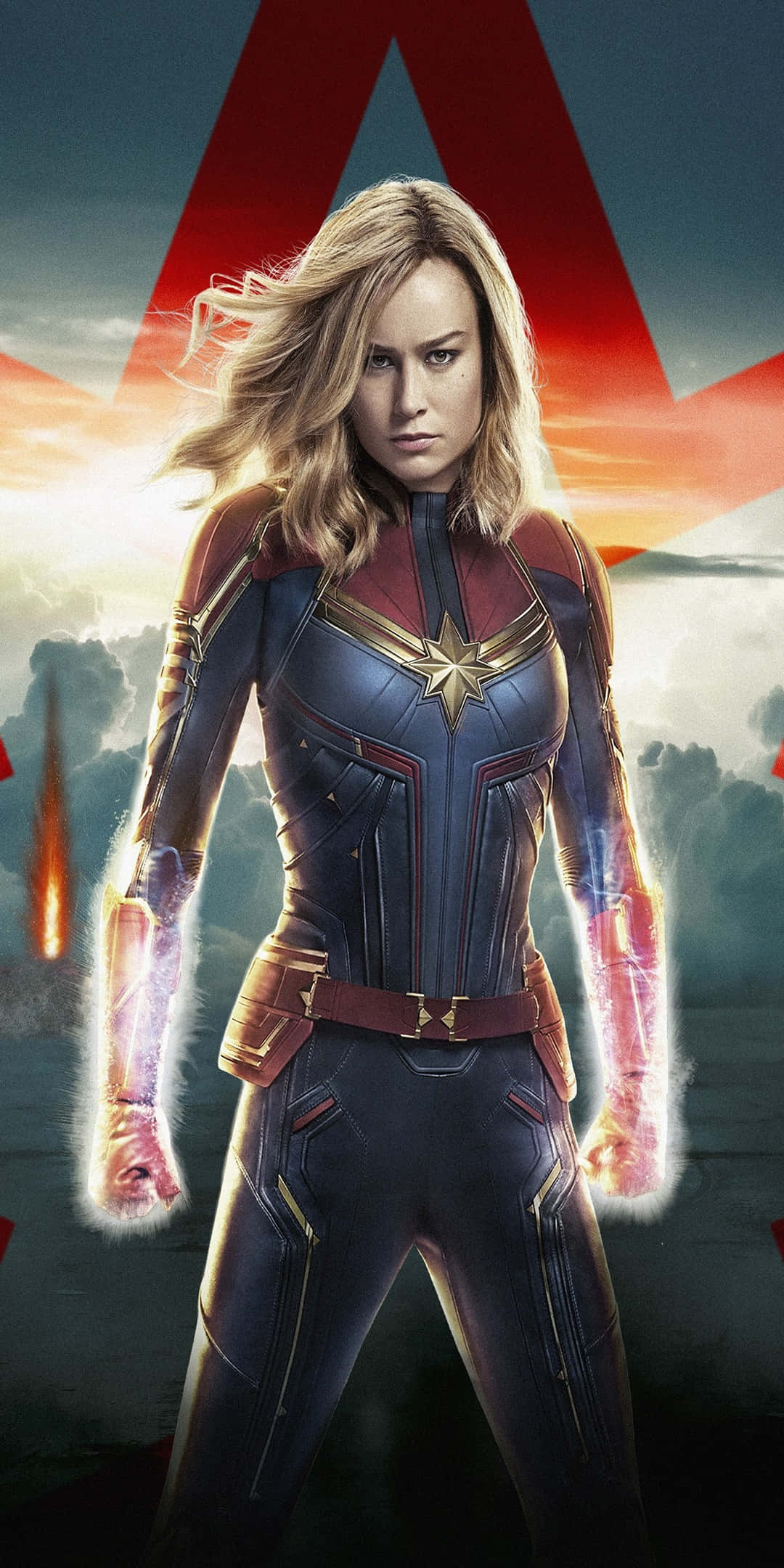 brie larson 桌布 壁紙 — 驚奇隊長在戲劇性的日落天空下英勇站立，拳頭散發出發光的能量。