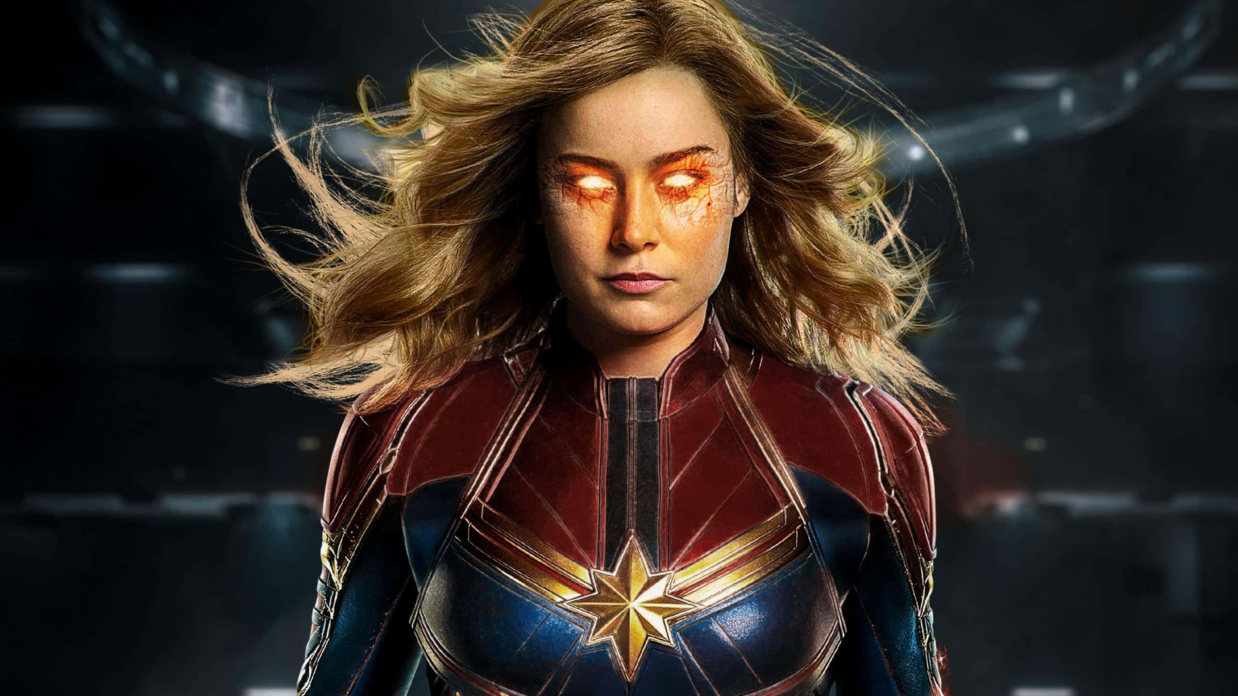 brie larson 桌布 壁紙 — 驚奇隊長在黑暗的未來設定中強勢站立，擁有發光的橙色眼睛和飄逸的金色頭髮。