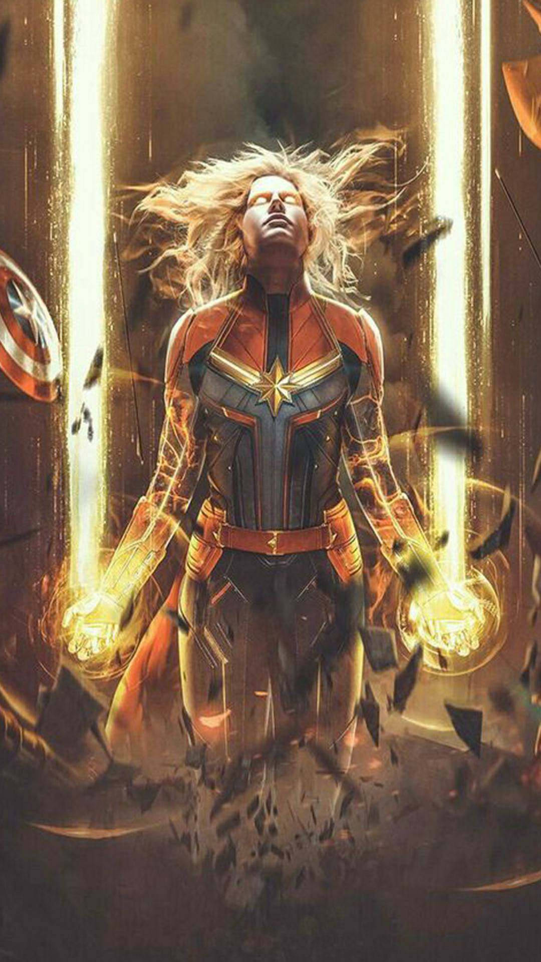 captain marvel iPhone 桌布 壁紙 — 驚奇隊長強勢地站在金色能量光束中，頭髮飄揚，拳頭發光，周圍碎片爆炸。