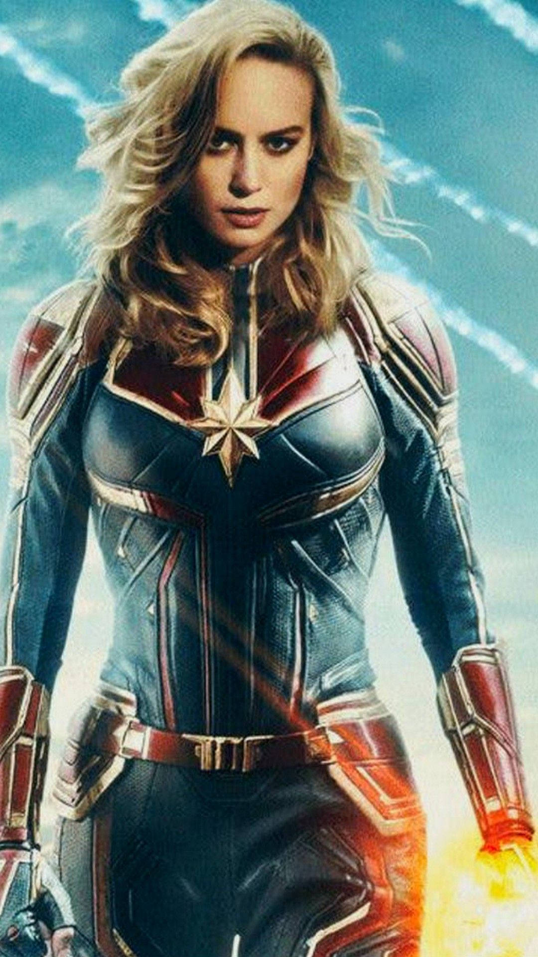 captain marvel iPhone 桌布 壁紙 — 驚奇隊長自信地穿著她的藍色、紅色和金色戰衣，在明亮的天空下，手中能量噼啪作響。