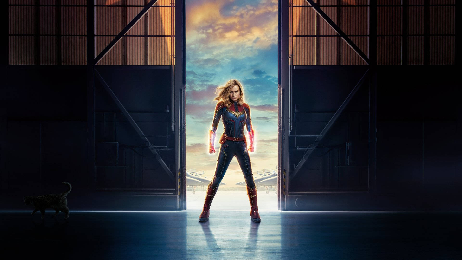 captain marvel 4K 桌布 壁紙 — 驚奇隊長英勇地站在機庫門口，金色光芒從她身後湧入。