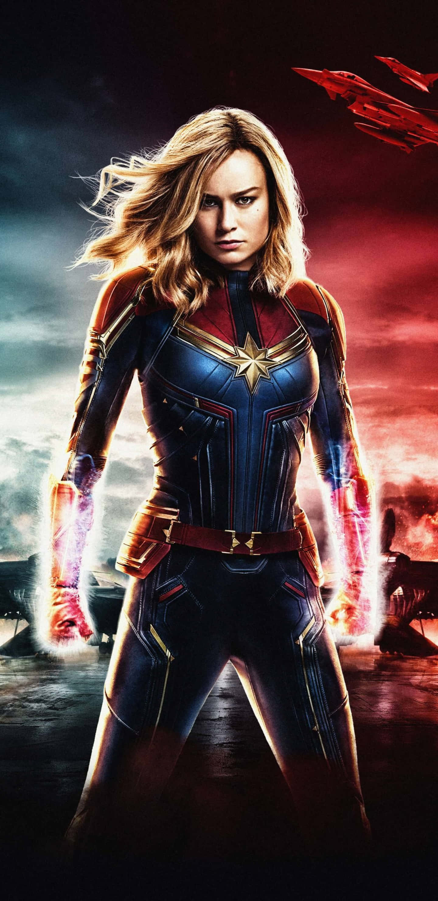 Pixel 3xl Captain Marvel 桌布 壁紙 — 驚奇隊長身穿藍紅戰衣，雙手發光，在火熱的天空和飛船前英勇站立。