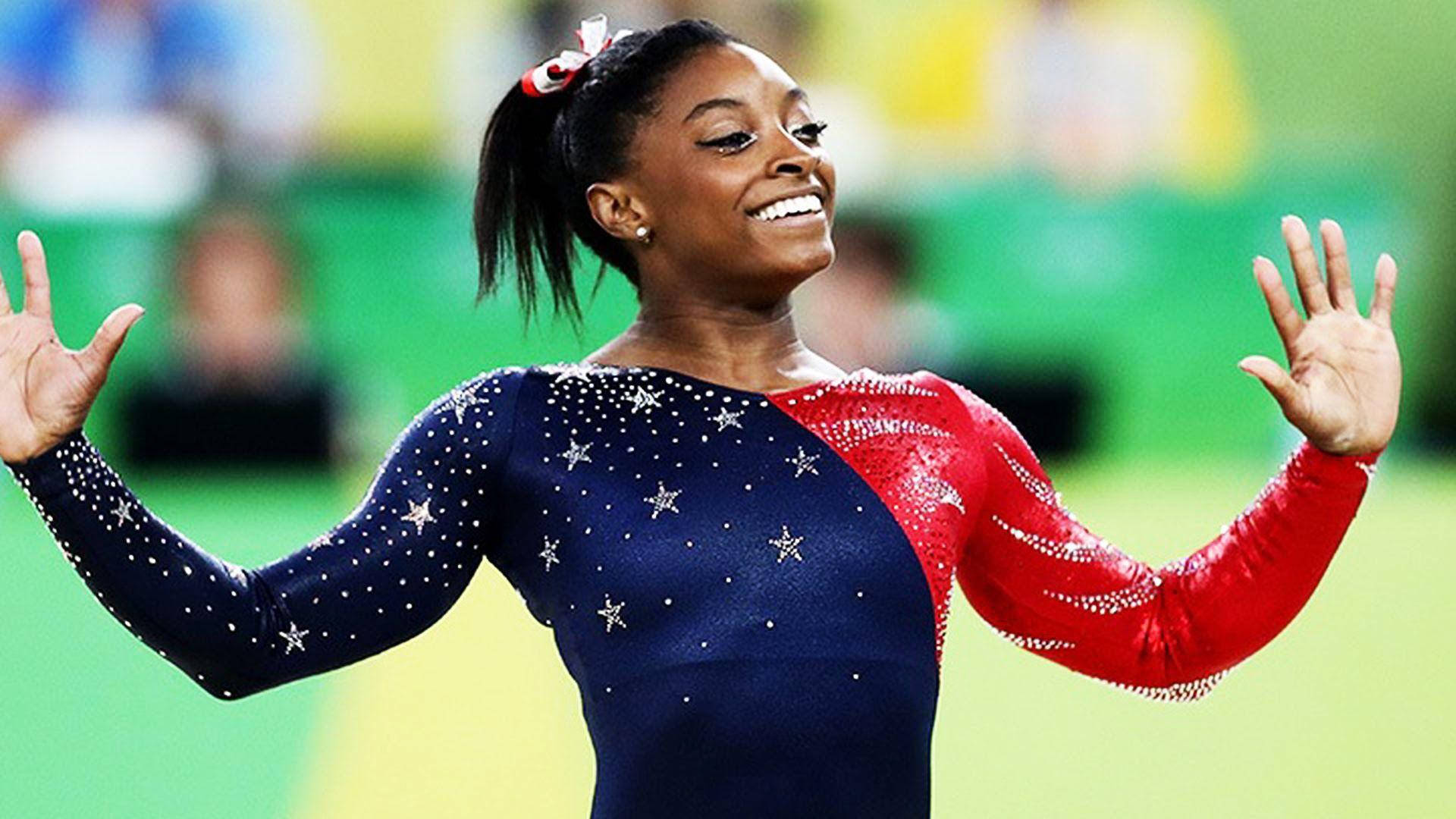 Simone Biles 桌布 壁紙 — 體操運動員Simone Biles身穿星條旗緊身衣，在勝利表演後張開雙臂，洋溢著喜悅。