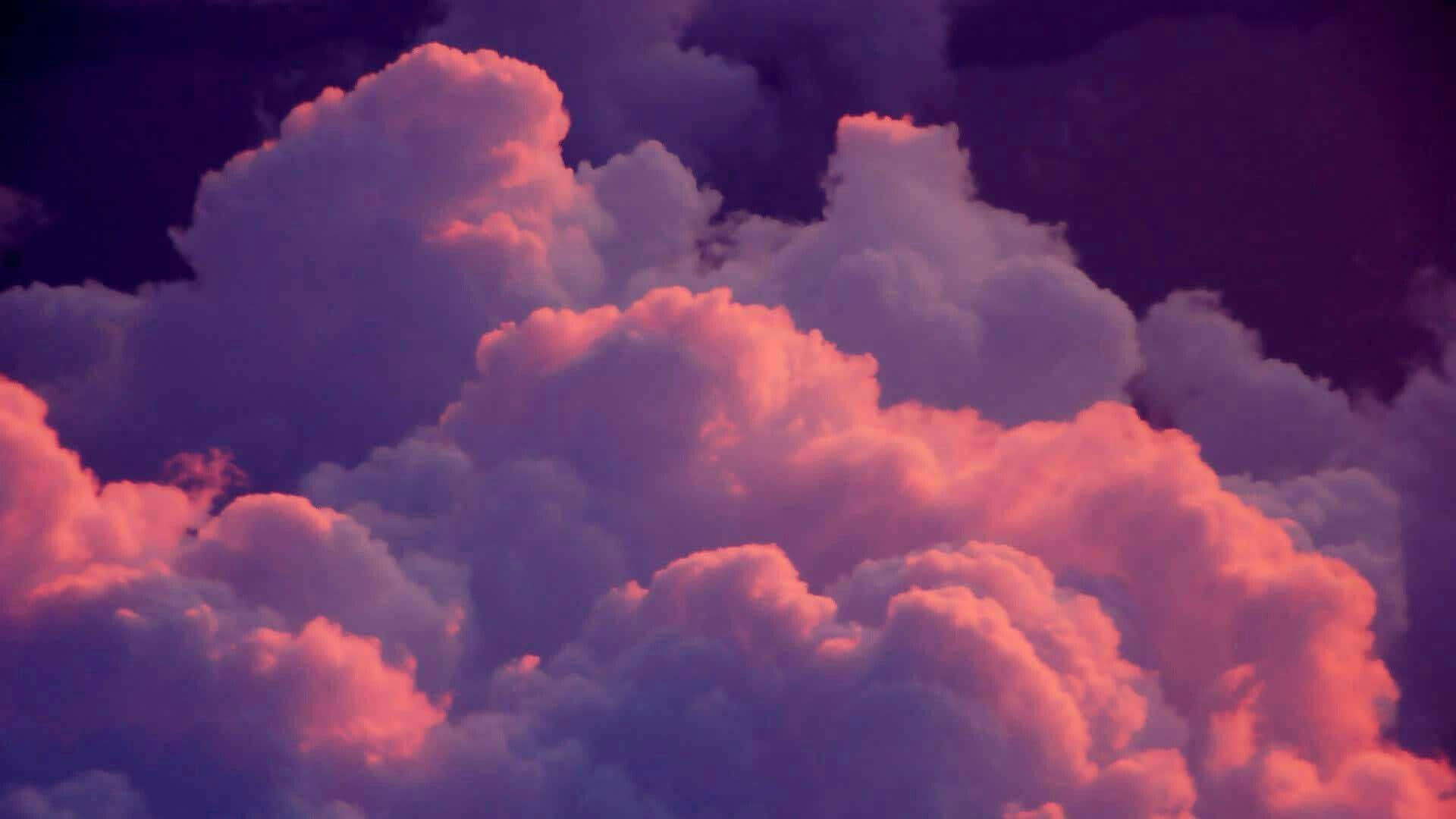 雲朵 桌布 壁紙 — 體積龐大的雲朵在黑暗的暮色天空中閃耀著火熱的粉紅色和深紫色色調。