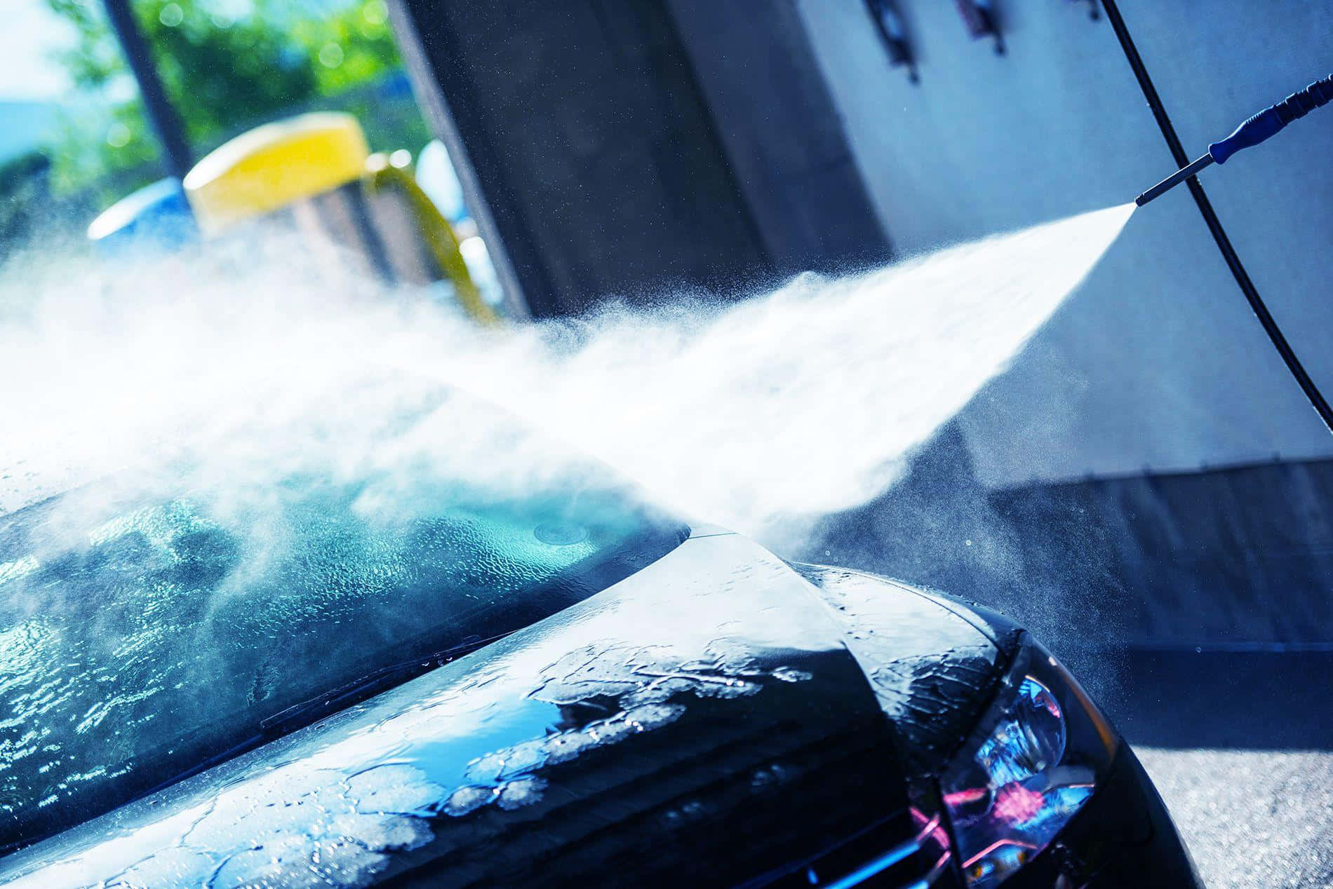 洗車 桌布 壁紙 — 高壓水柱橫掃洗車場中黑色汽車的光亮引擎蓋，將水霧噴灑到明亮的陽光中。