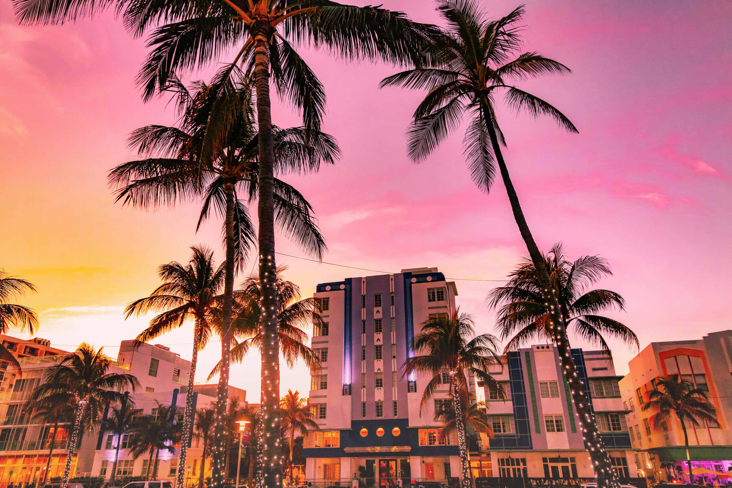 Miami 桌布 壁紙 — 高大的棕櫚樹在邁阿密海灘色彩繽紛的裝飾藝術建築上方勾勒出充滿活力的日落。