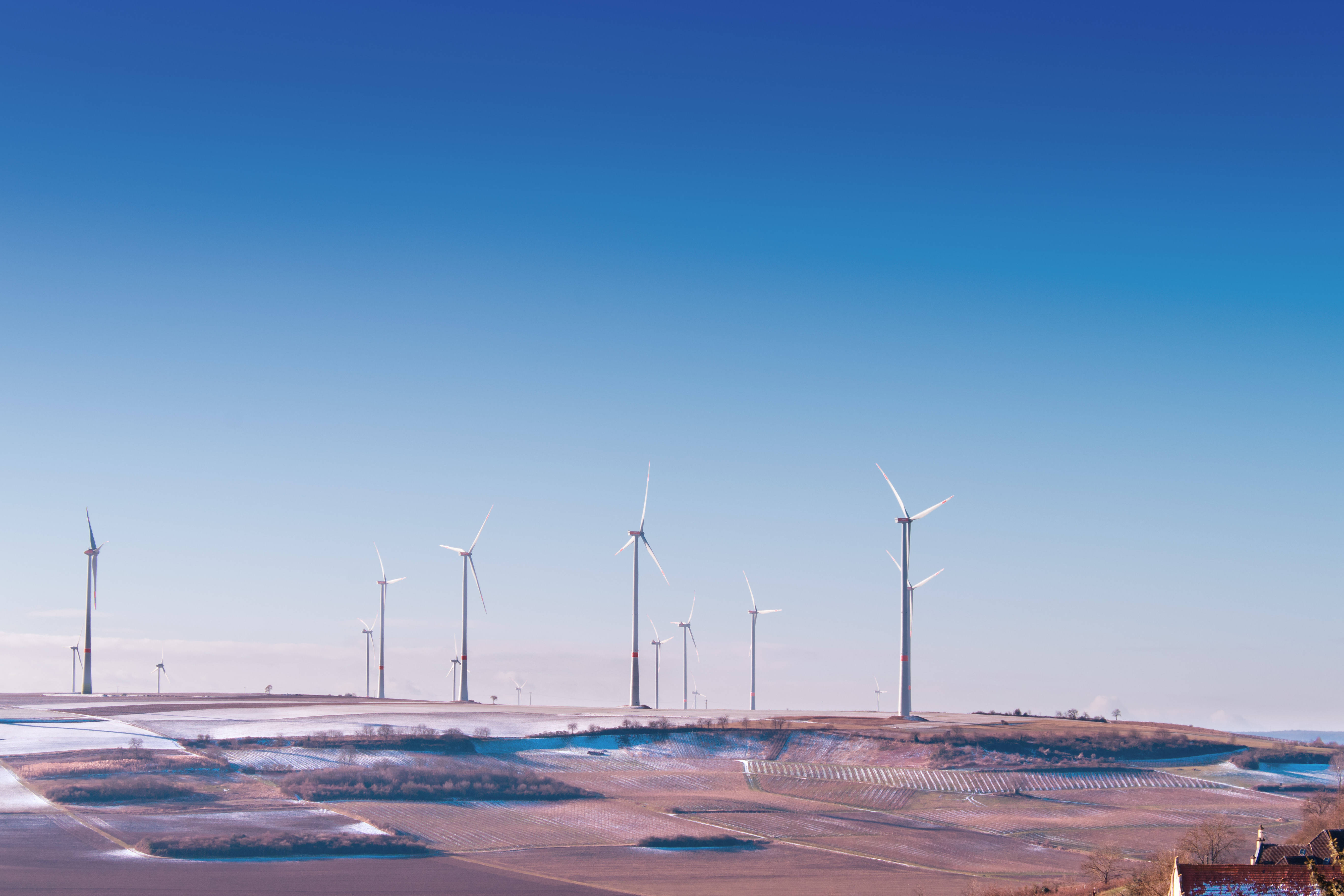 Energy 桌布 壁紙 — 高大的白色風力渦輪機在晴朗的藍天下排列在雪地上。