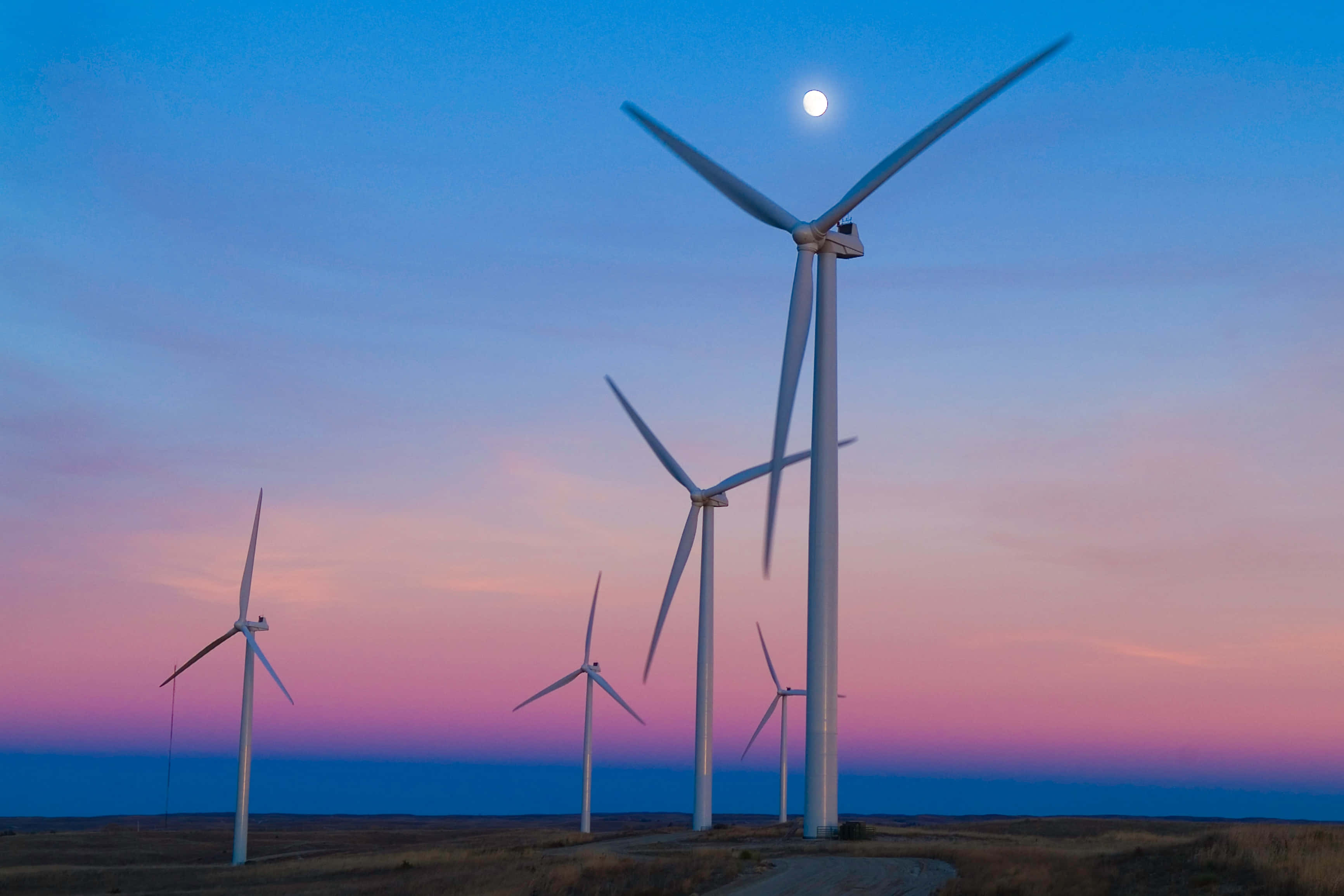 Wind 桌布 壁紙 — 高大的白色風力渦輪機矗立在染上粉紅與藍色調的暮色天空下，月亮正冉冉升起。