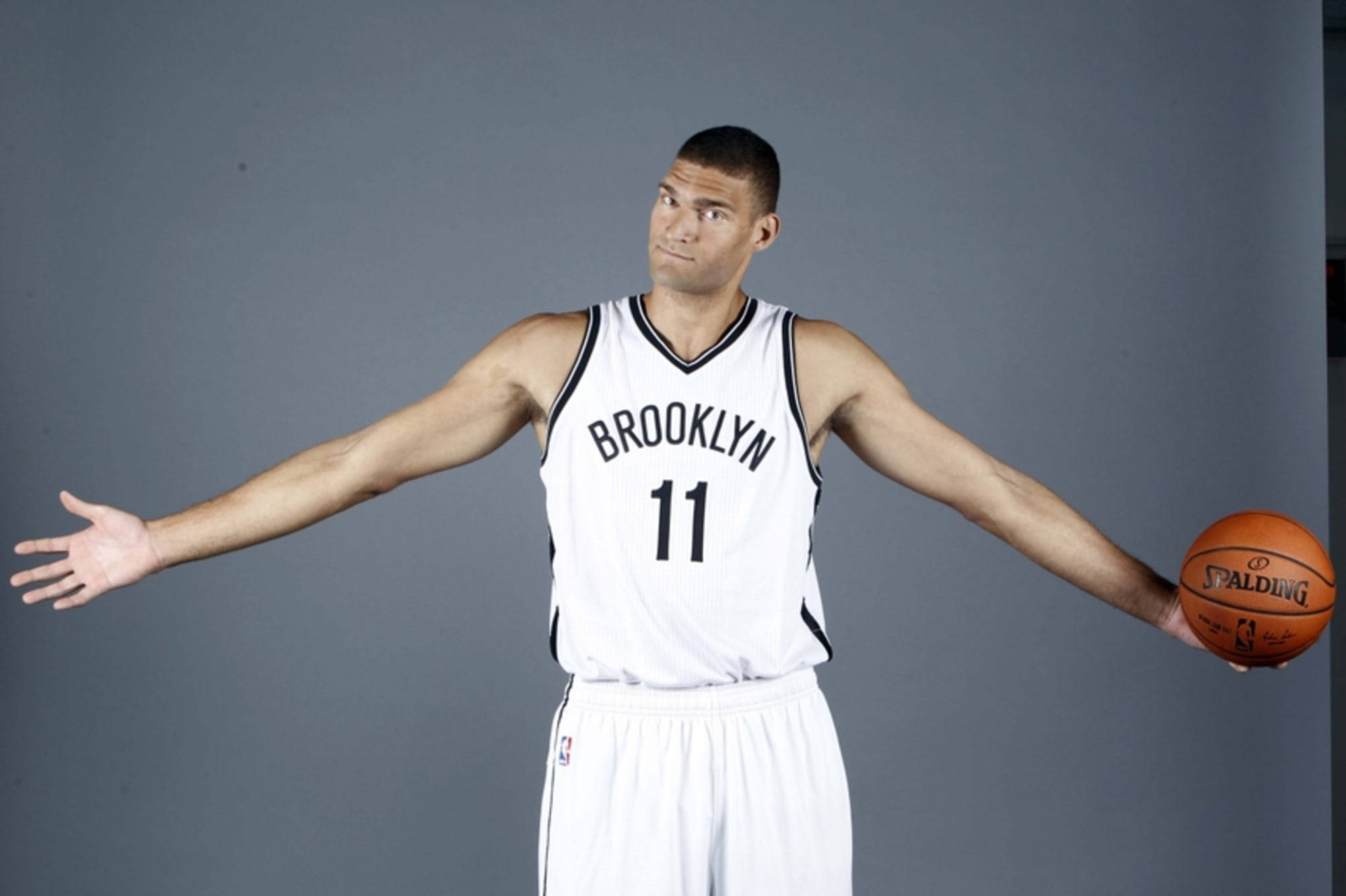 Brook 桌布 壁紙 — 高大的籃球運動員身穿布魯克林球衣，在灰色工作室背景下張開雙臂持球。