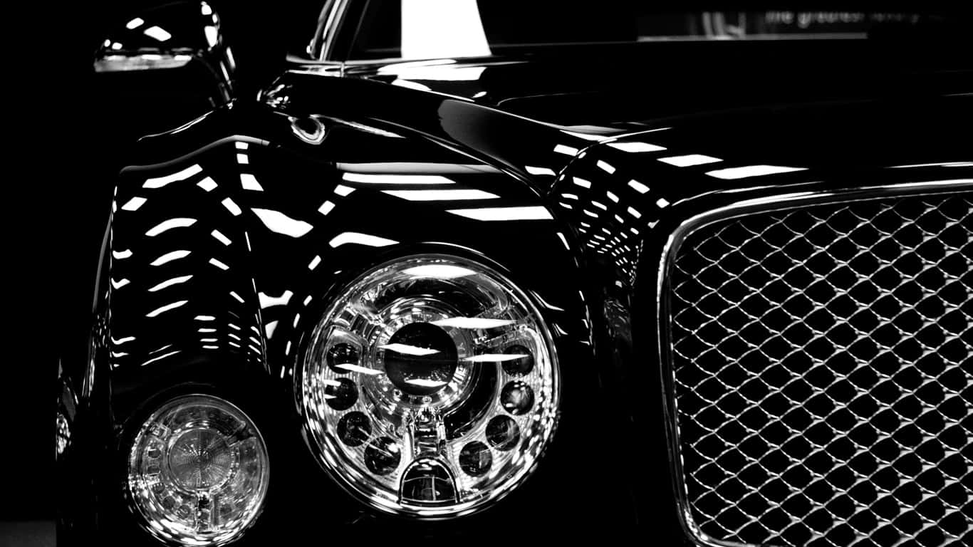 1366x768 Bentley 桌布 壁紙 — 高對比度黑白特寫，捕捉豪華汽車閃亮的前格柵和車頭燈反射光線。