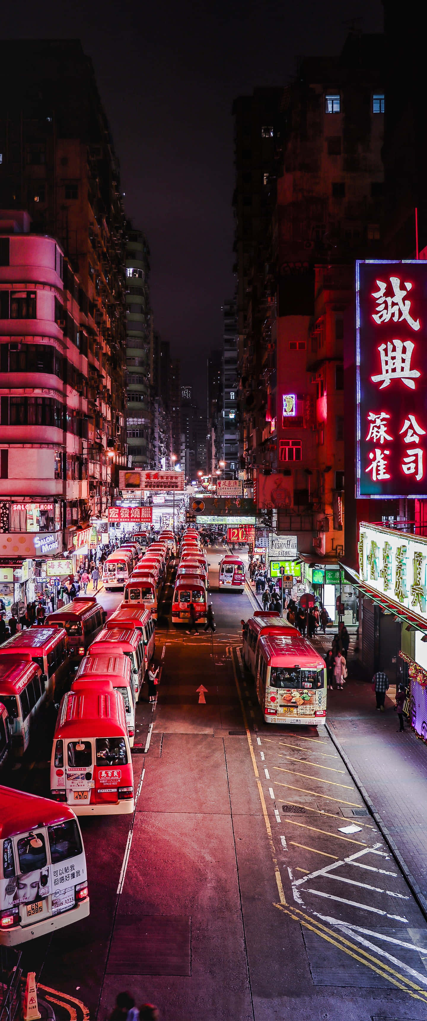 Street 桌布 壁紙 — 高樓大廈上掛滿紅色巴士和閃爍霓虹燈牌的密集城市中一條充滿活力的夜晚街道。