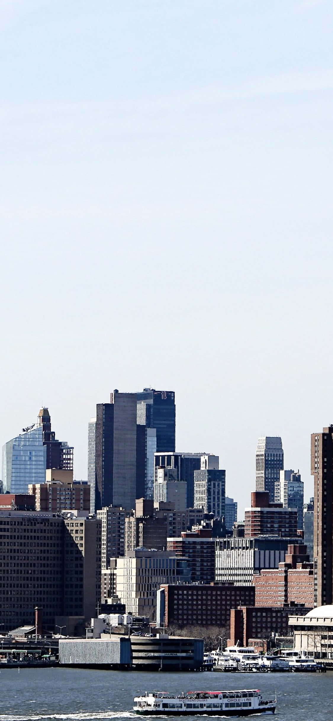 New York 桌布 壁紙 — 高樓大廈密集的城市天際線全景，以及朦朧天空下水面上的渡輪。