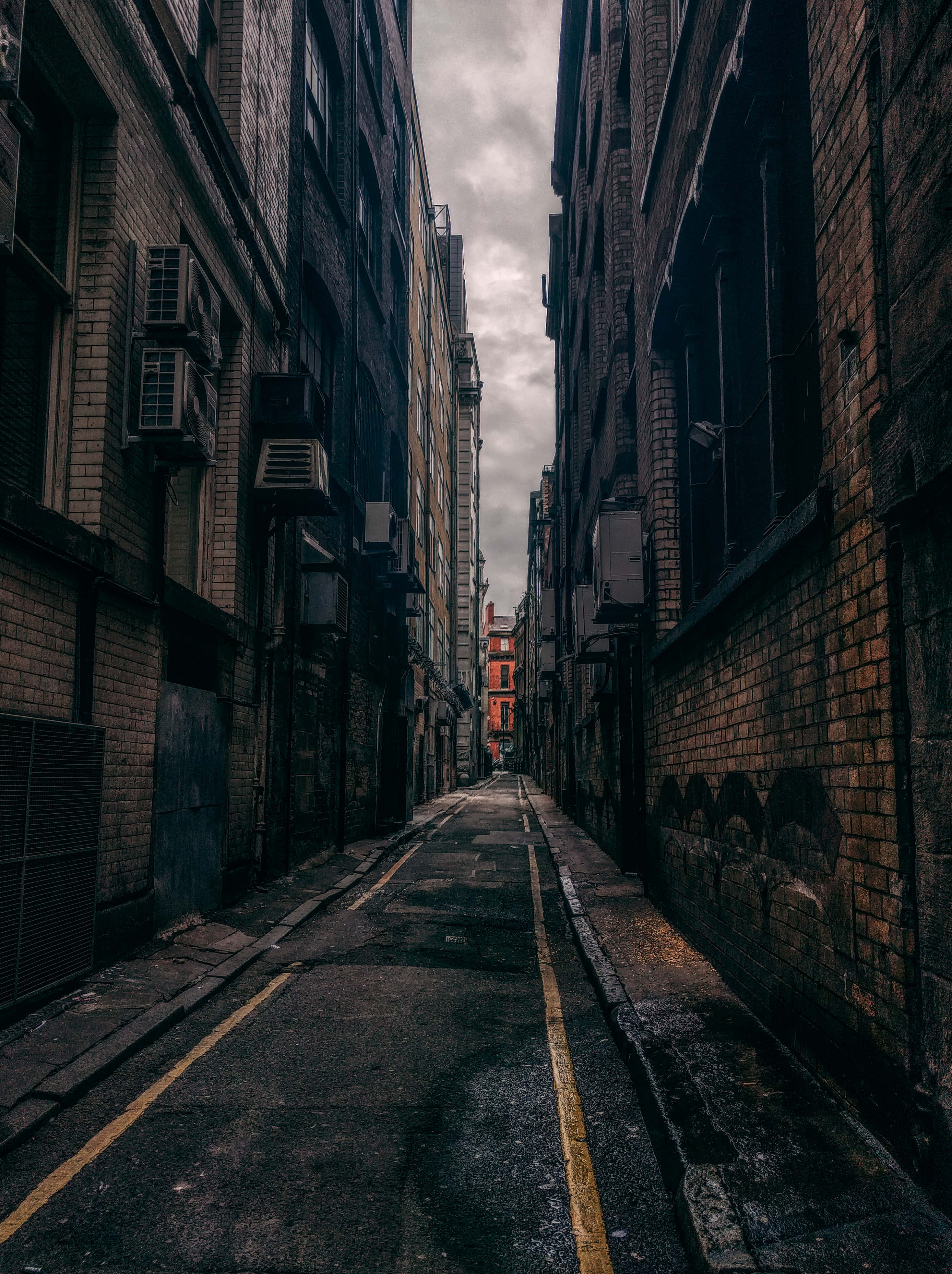 Building 桌布 壁紙 — 高樓磚建築之間狹窄的城市小巷，陰天，黃色道路標線。
