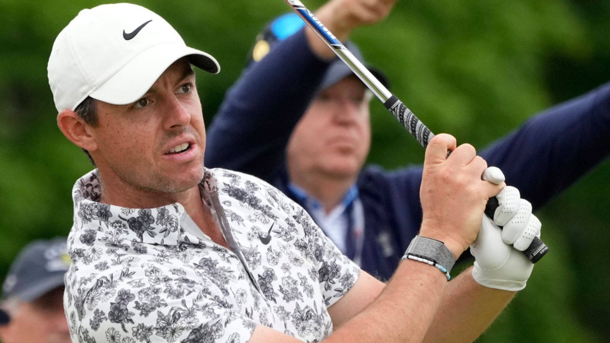 Man 桌布 壁紙 — 高爾夫球手 Rory McIlroy 揮桿中，身穿花卉圖案襯衫和白色帽子，背景為模糊的綠色。